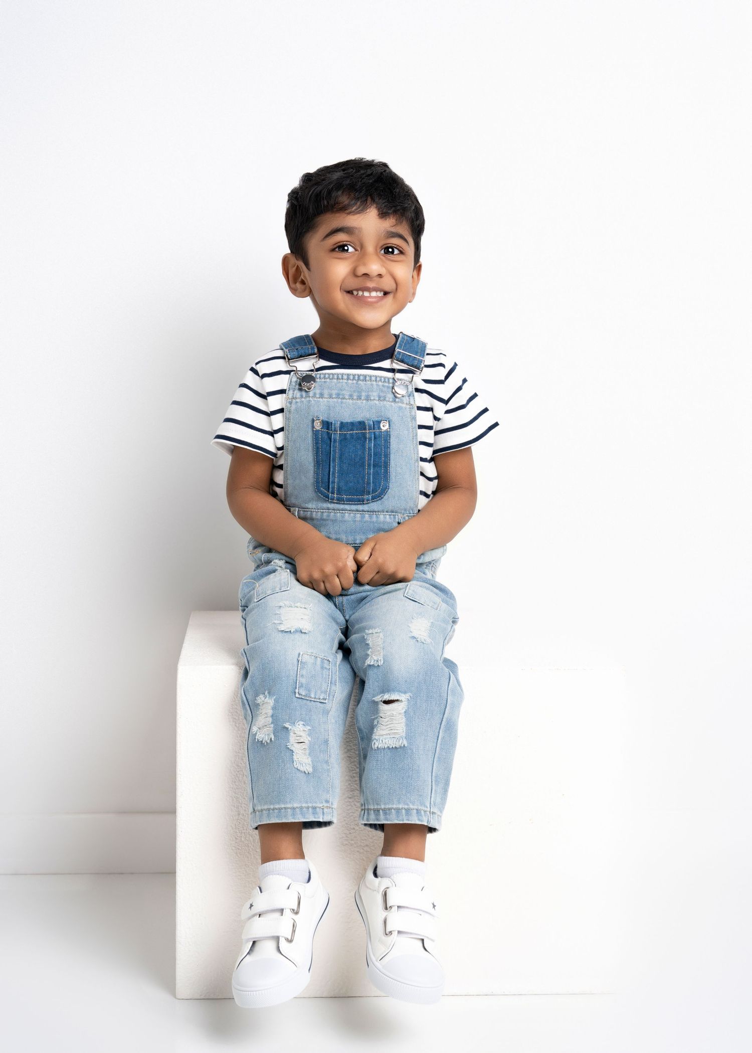 a boy smiles while sitting on a white cube