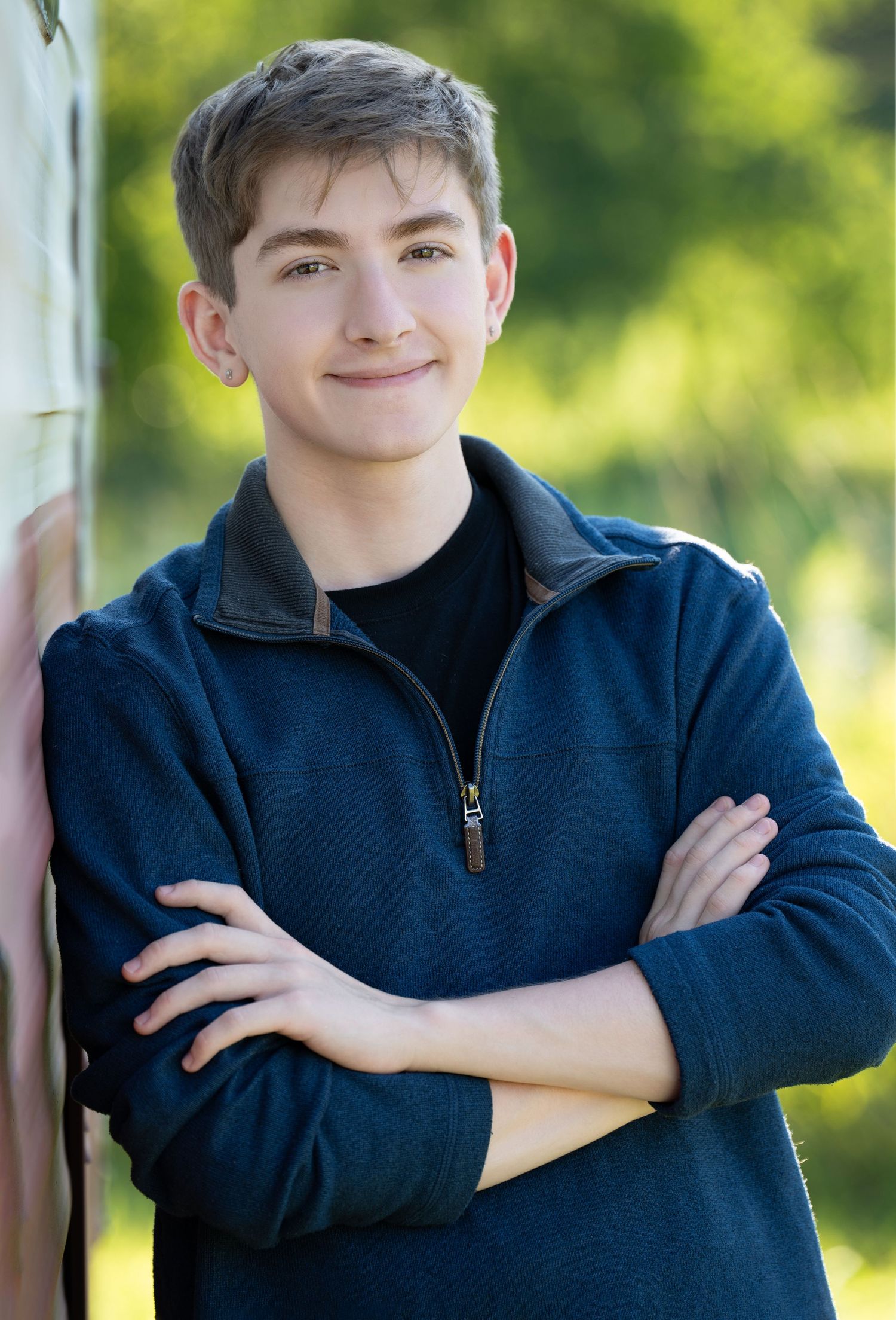 a young man smiles with his arms crossed