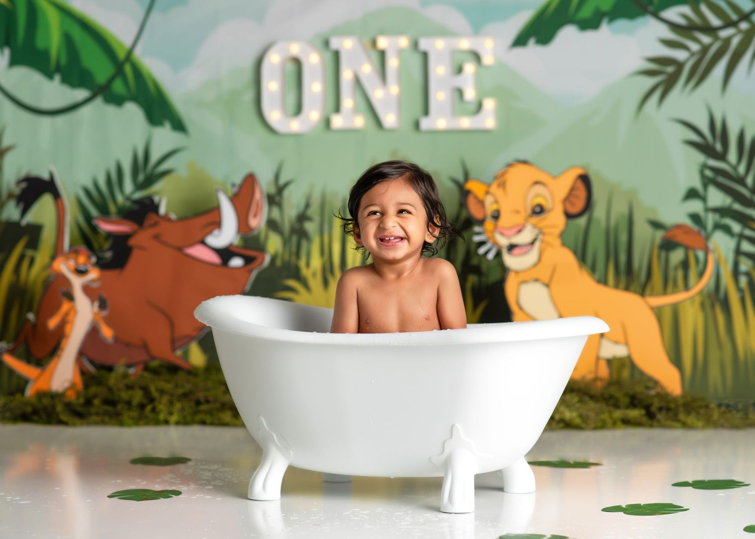 a boy smiles from a tiny bathtub in a lion king themed studio