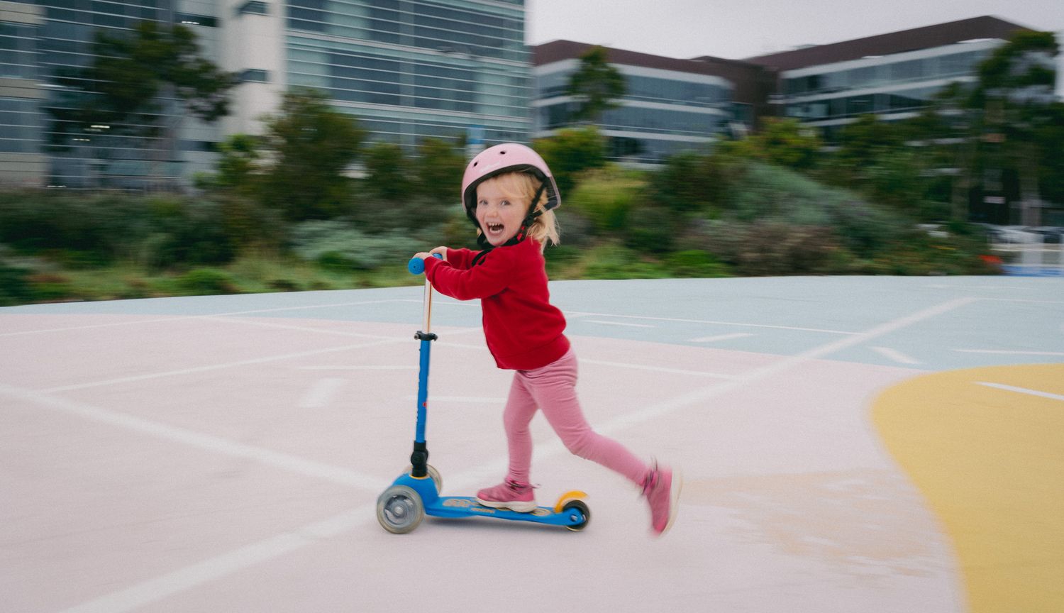 A series of action shots showing someone riding a blue scooter on a paved path in an outdoor setting.