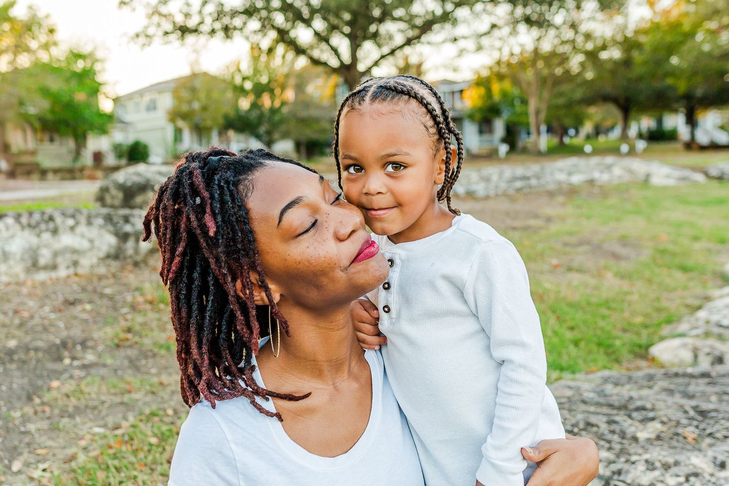 A tender moment shared between parent and child outdoors in a park setting during golden hour.