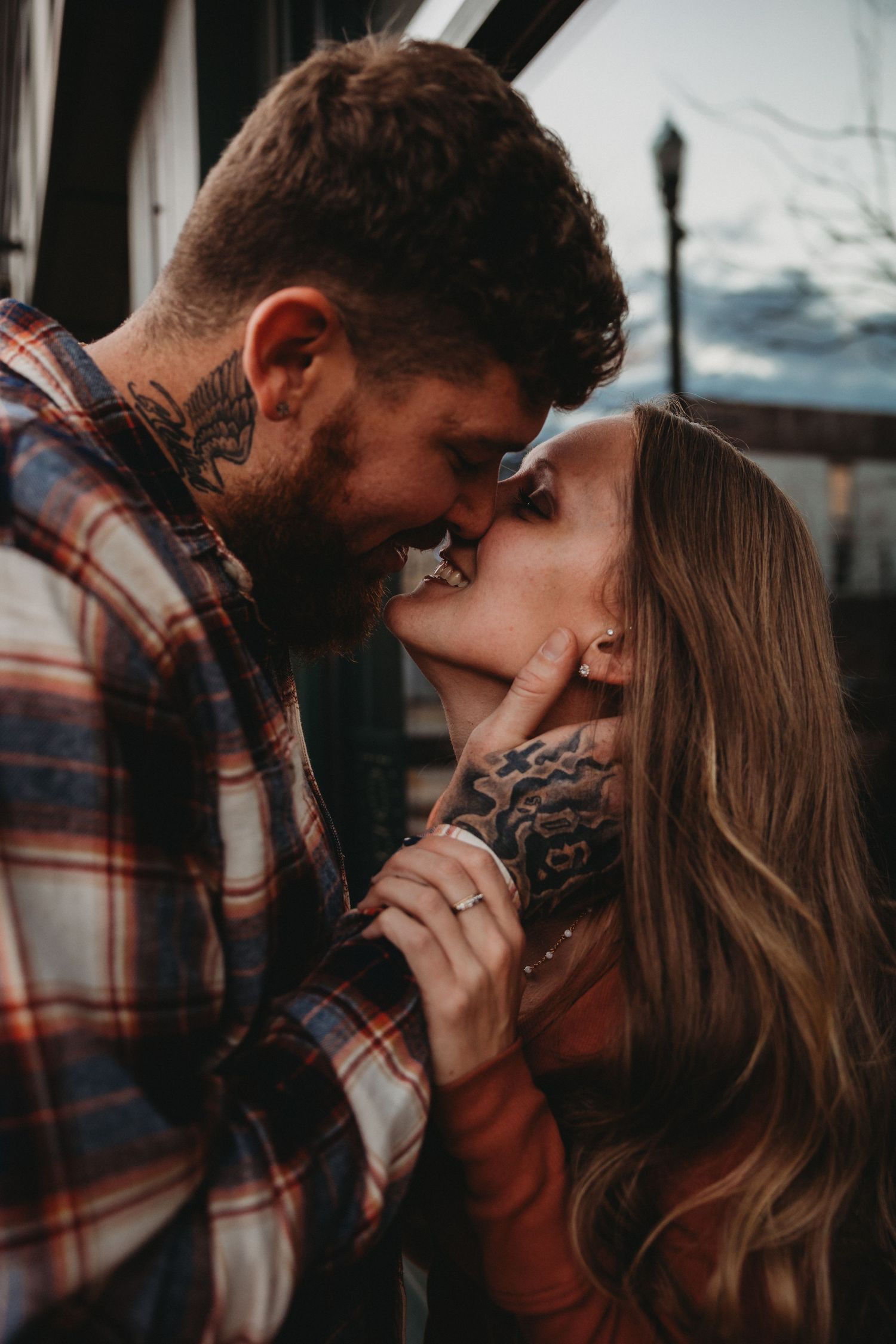 Intimate close-up of couple sharing tender moment in rustic outdoor setting.