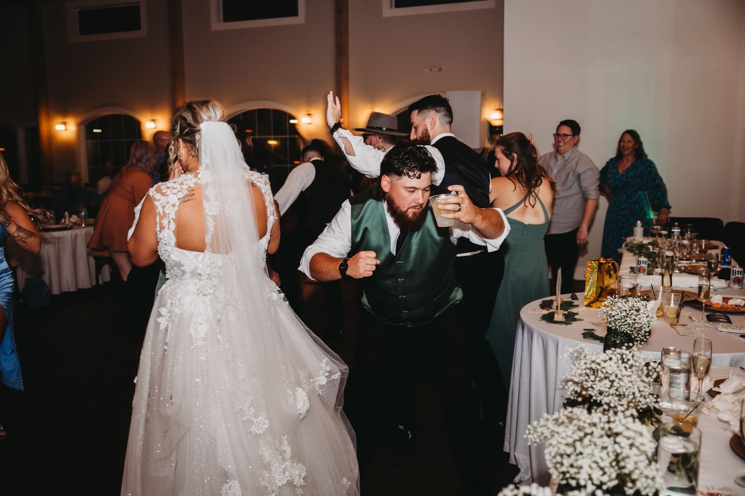 Newlyweds dancing together at their wedding reception surrounded by elegant table settings.