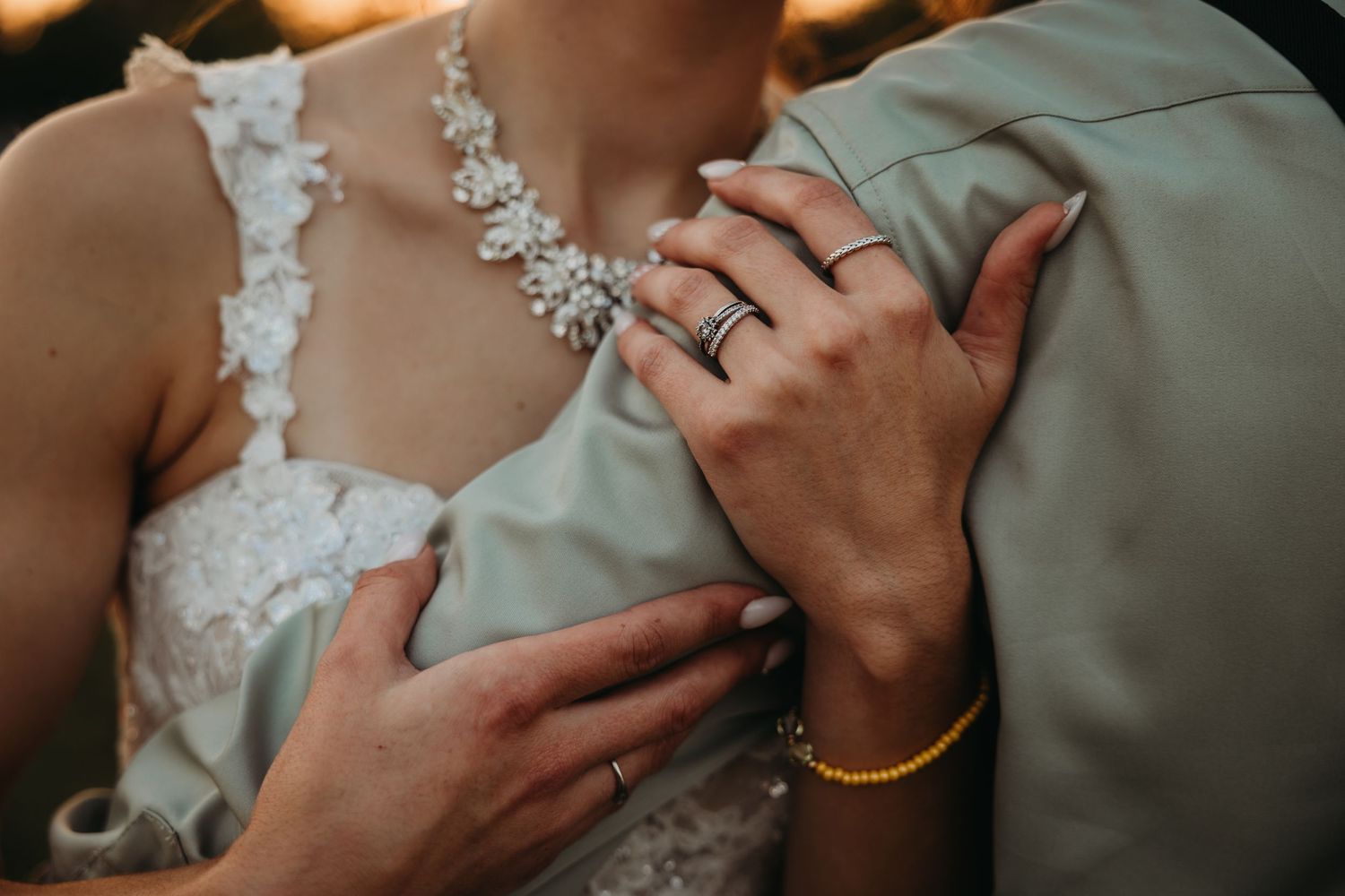 Close-up detail of wedding jewelry and lace dress details.