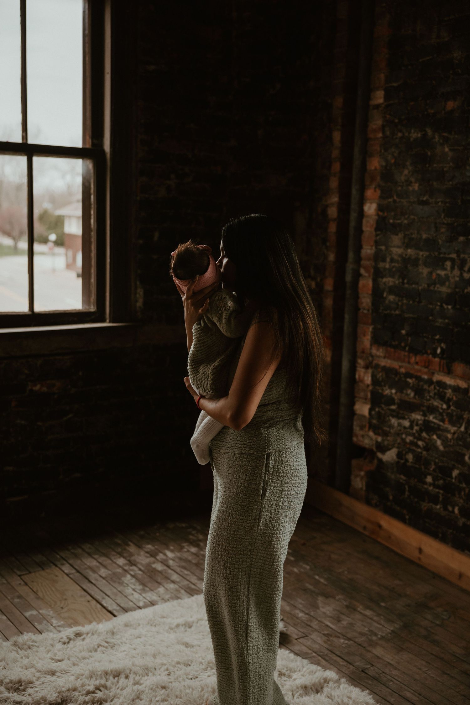 A tender moment captured in a rustic room with natural light streaming through a window.
