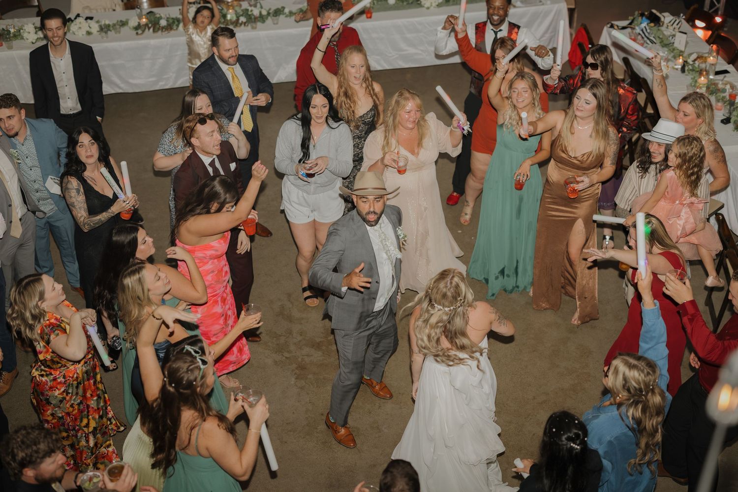 Wedding guests dancing and celebrating on a crowded dance floor at a reception.