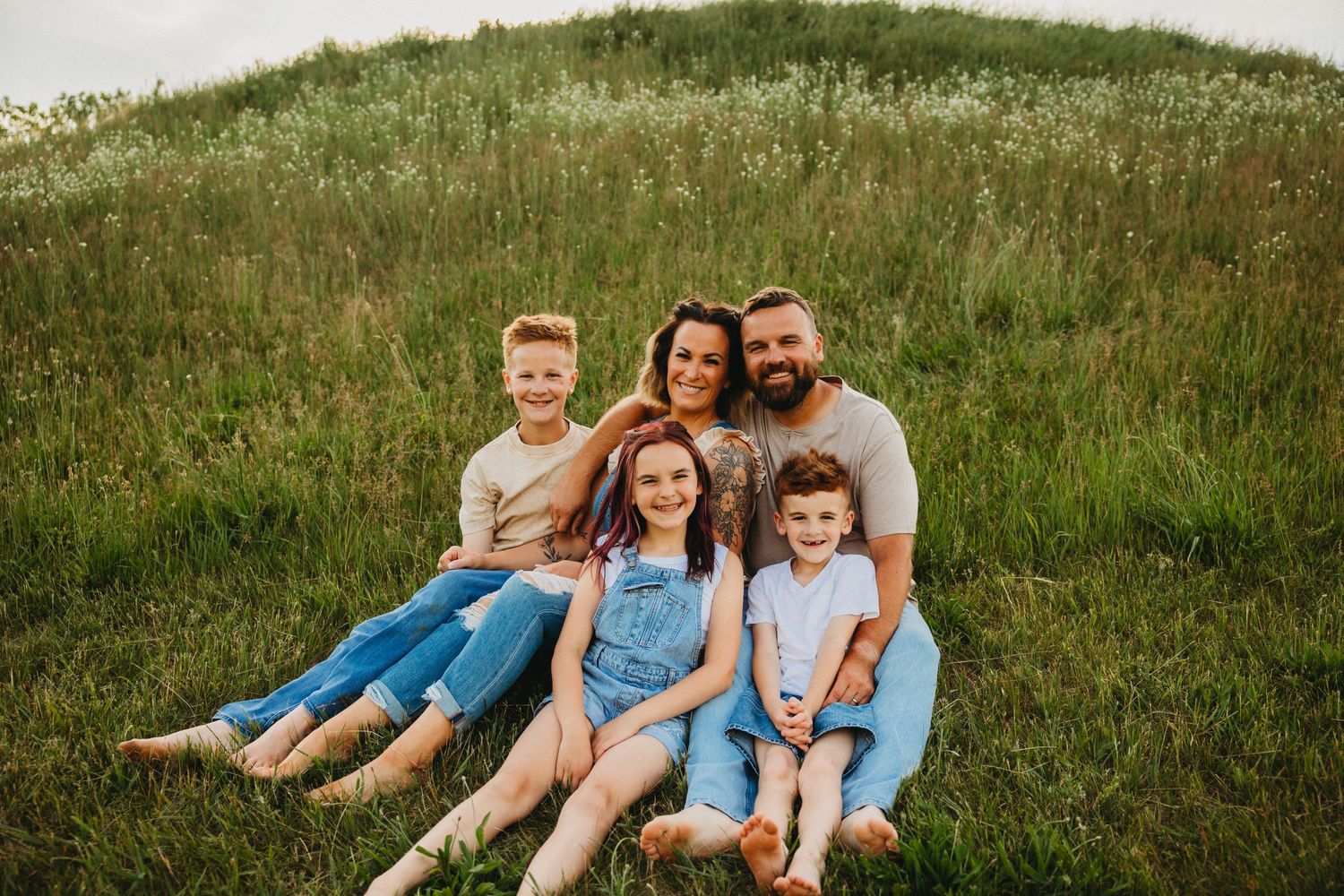 Group sits together on grassy hillside wearing coordinated blue and white outfits.