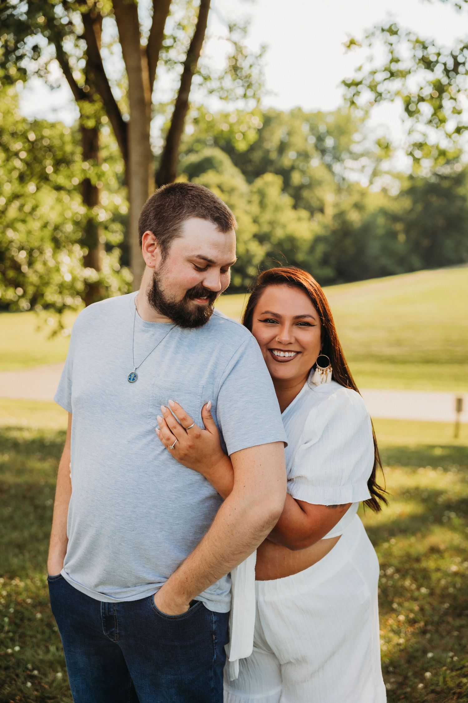 Happy couple sharing intimate moment outdoors in sunny park setting.
