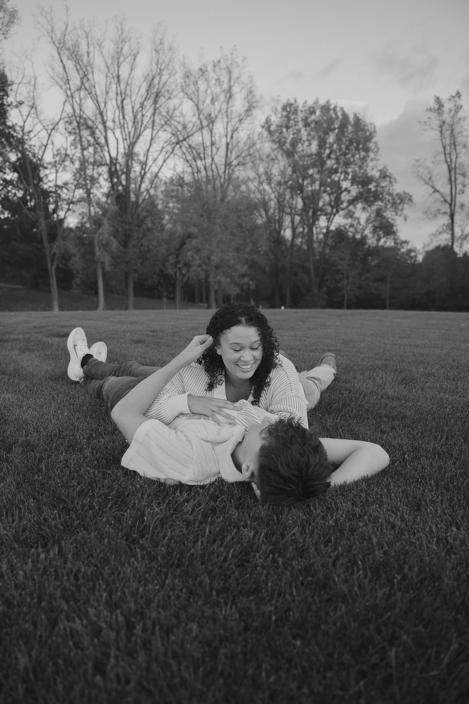 Black and white photo series showing a person in white clothing lying in a grassy field on a cloudy day.