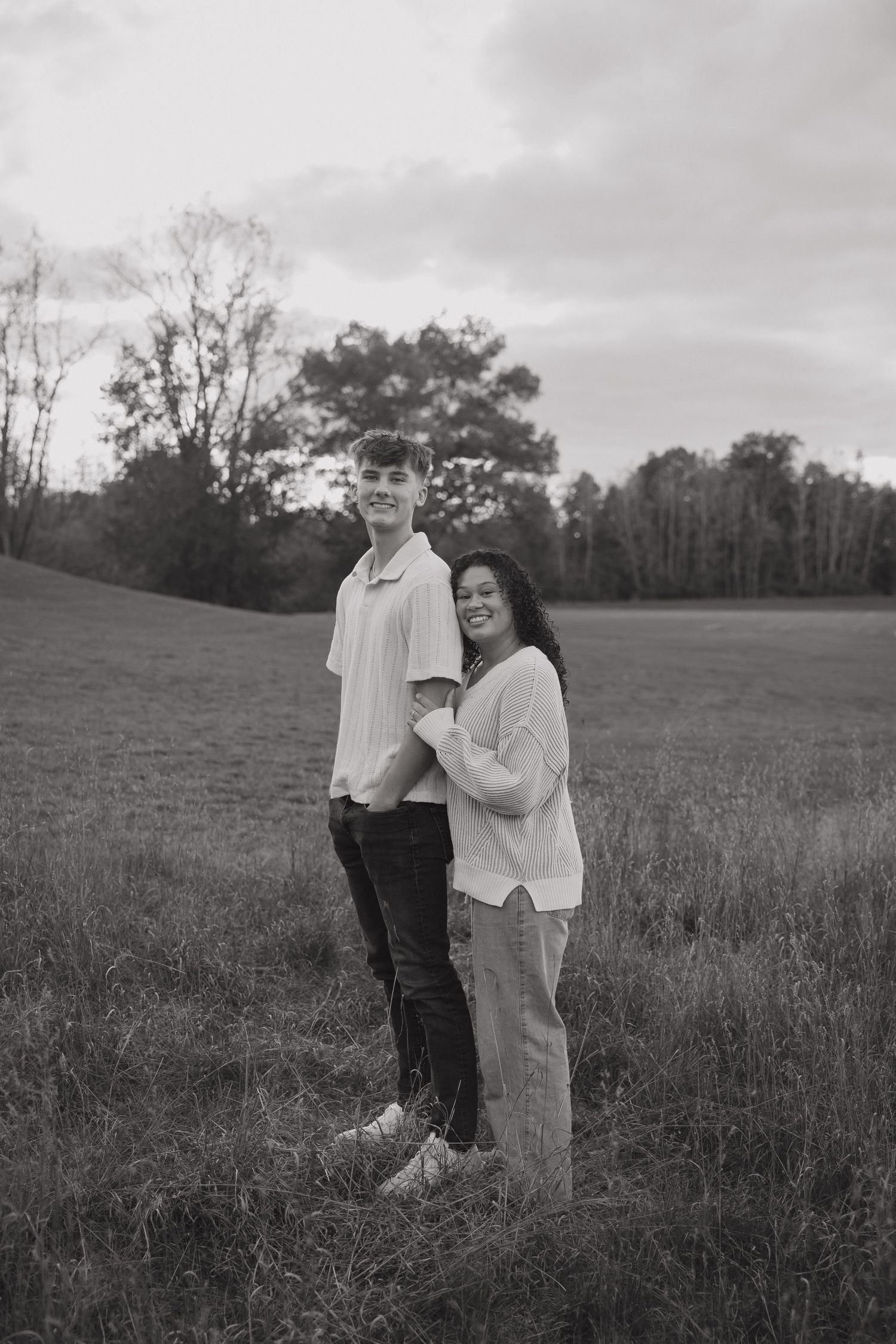 A couple shares a tender moment together in a grassy field during golden hour.