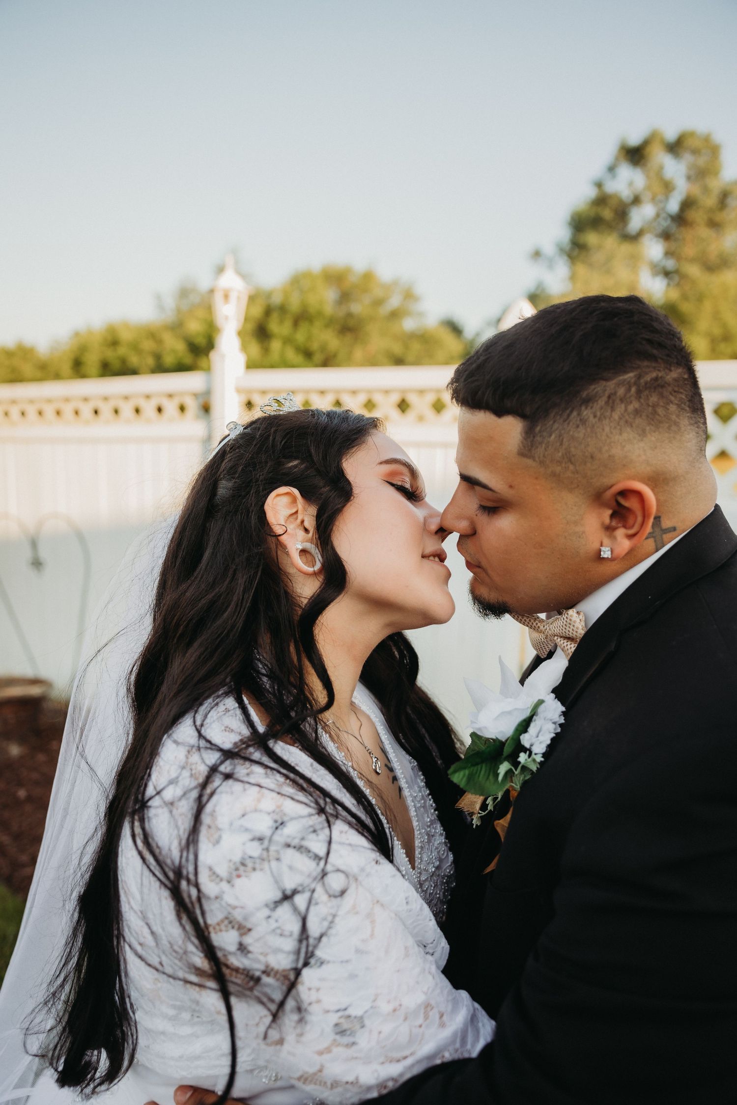 Romantic moment between newlyweds sharing a kiss outdoors.