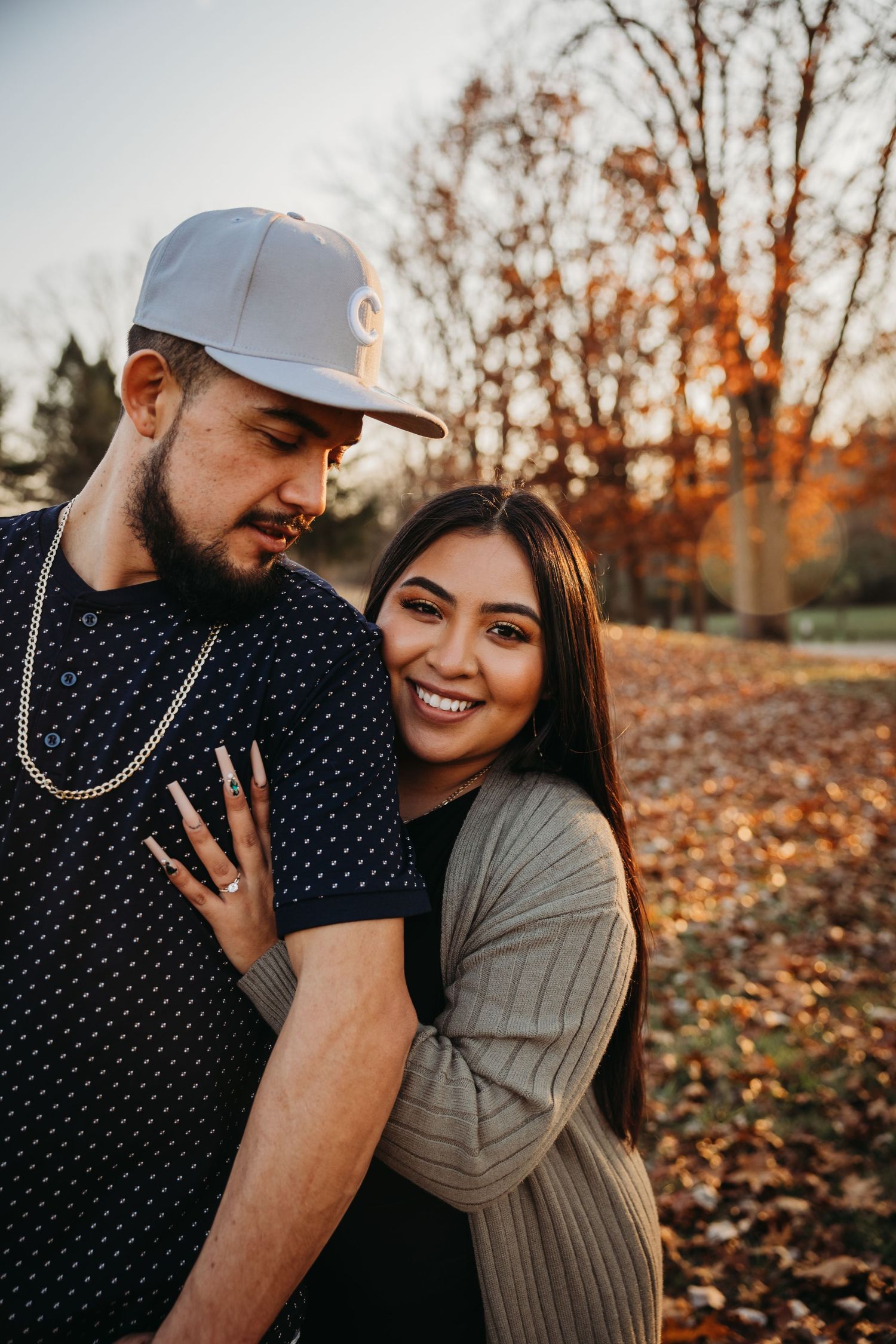 Couple sharing tender moment in autumn setting with warm sunset lighting.