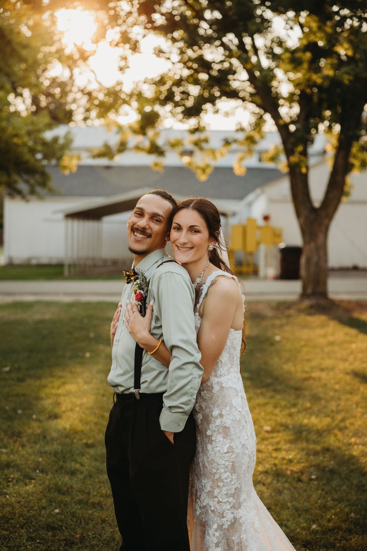 A couple poses together during golden hour in their wedding attire.
