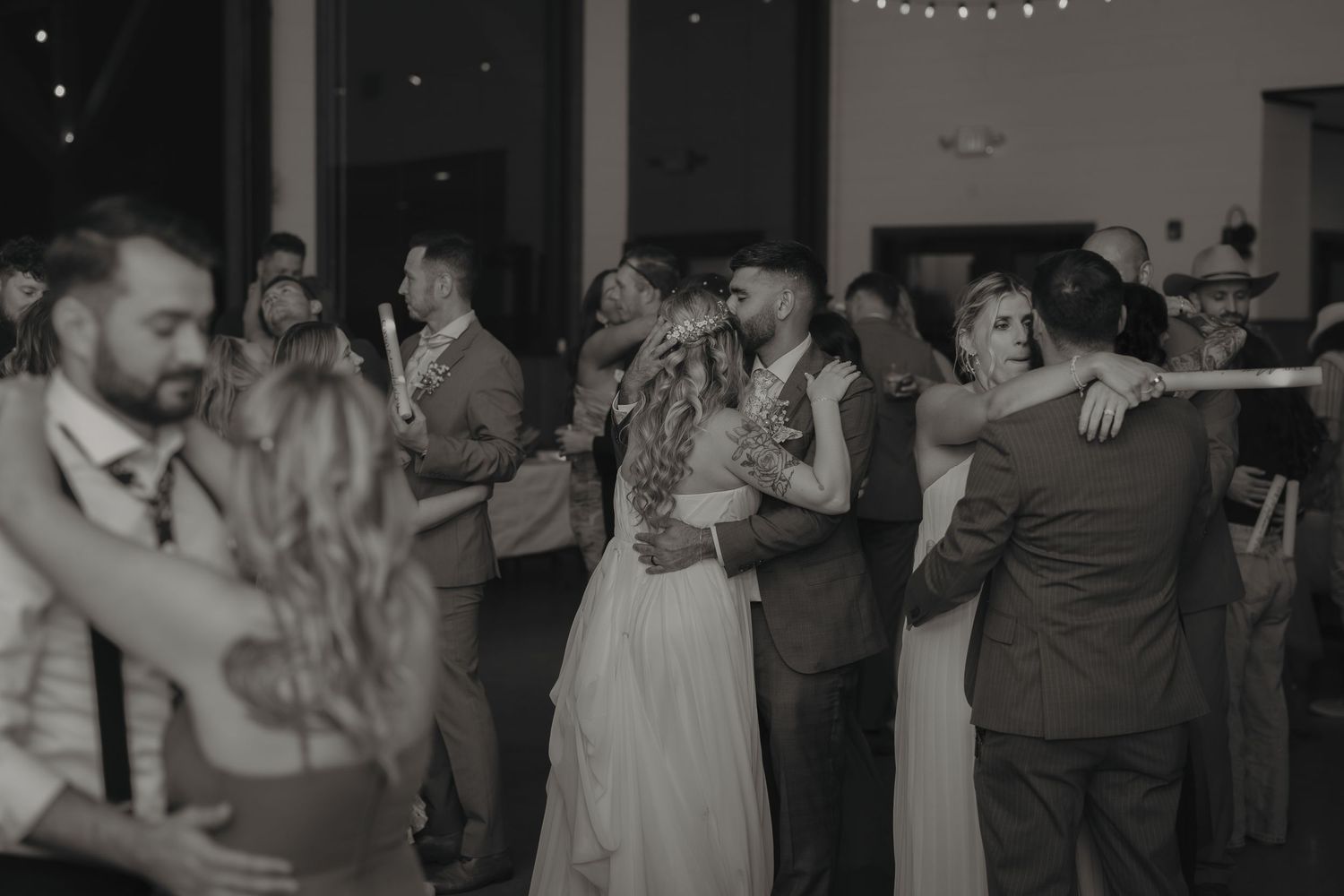 Black and white photo of wedding reception dance floor with guests celebrating.