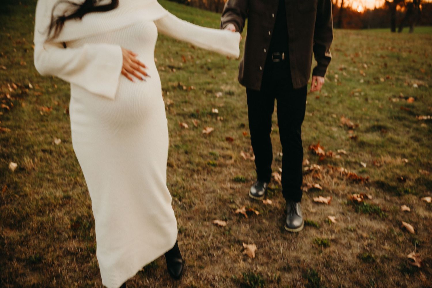 Maternity photoshoot in park showing couple's silhouette against autumn background.