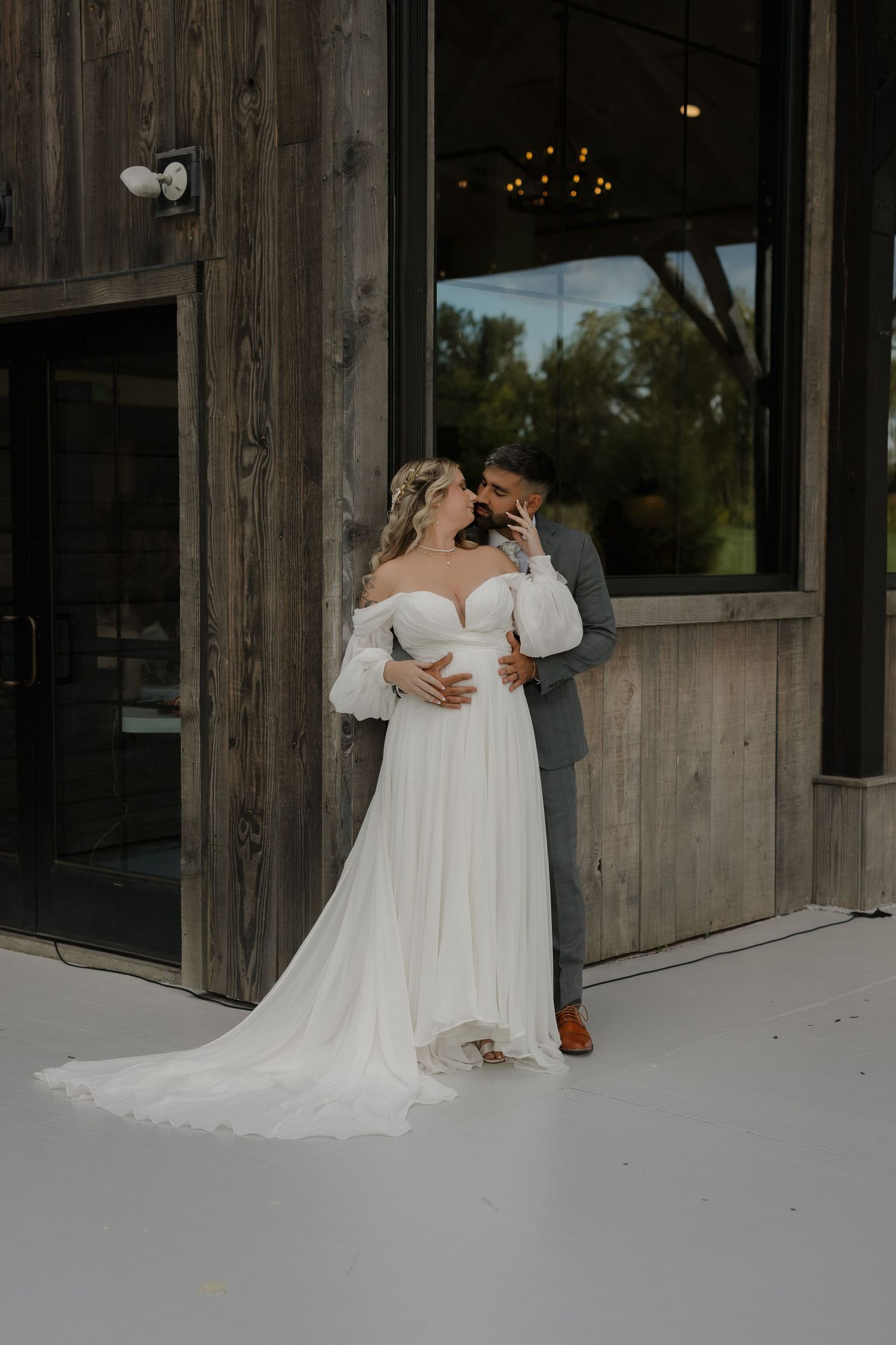 A romantic wedding moment captured outside a rustic wooden barn venue.