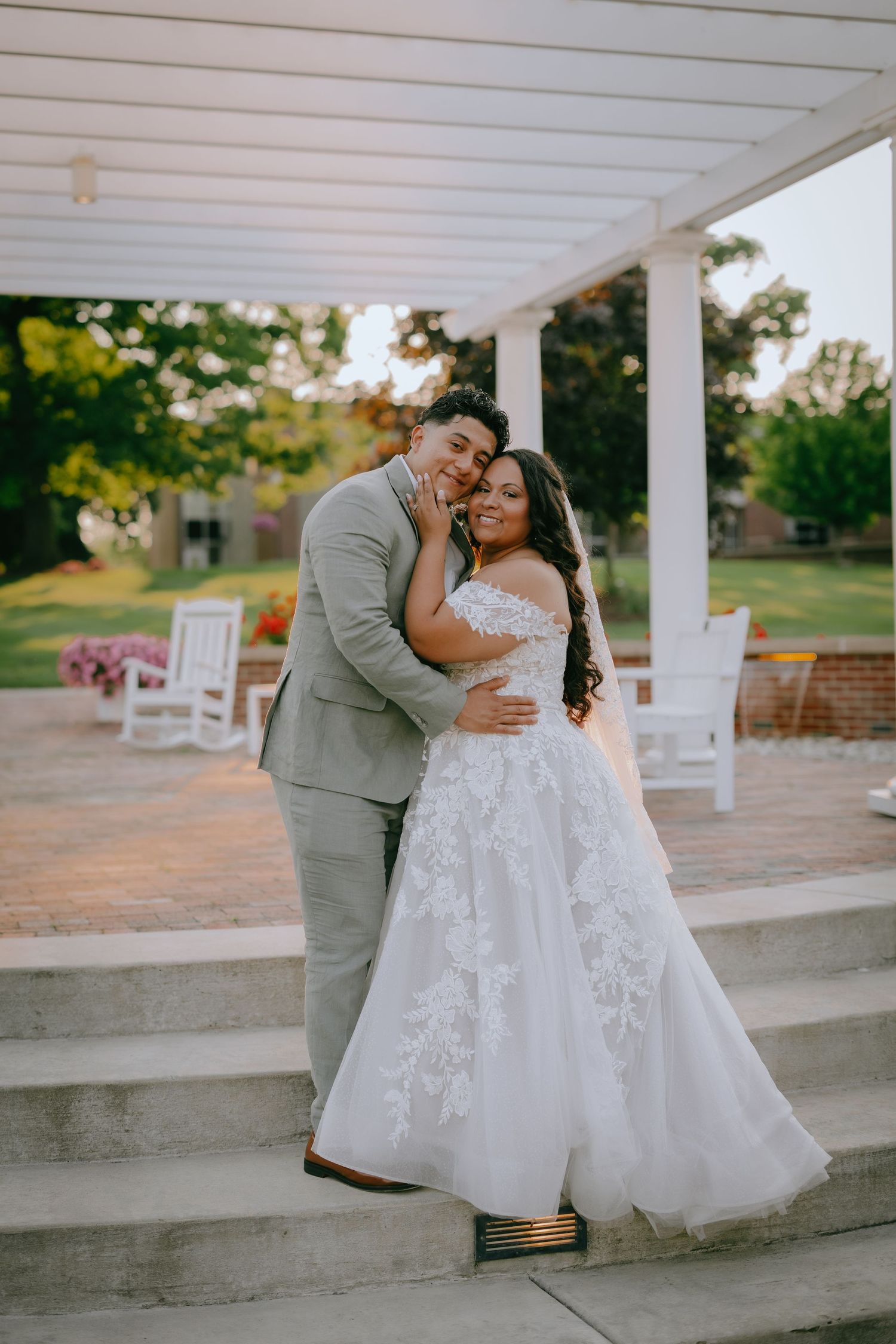 A tender wedding moment shared on a porch with white rocking chairs and warm sunset lighting in the background.