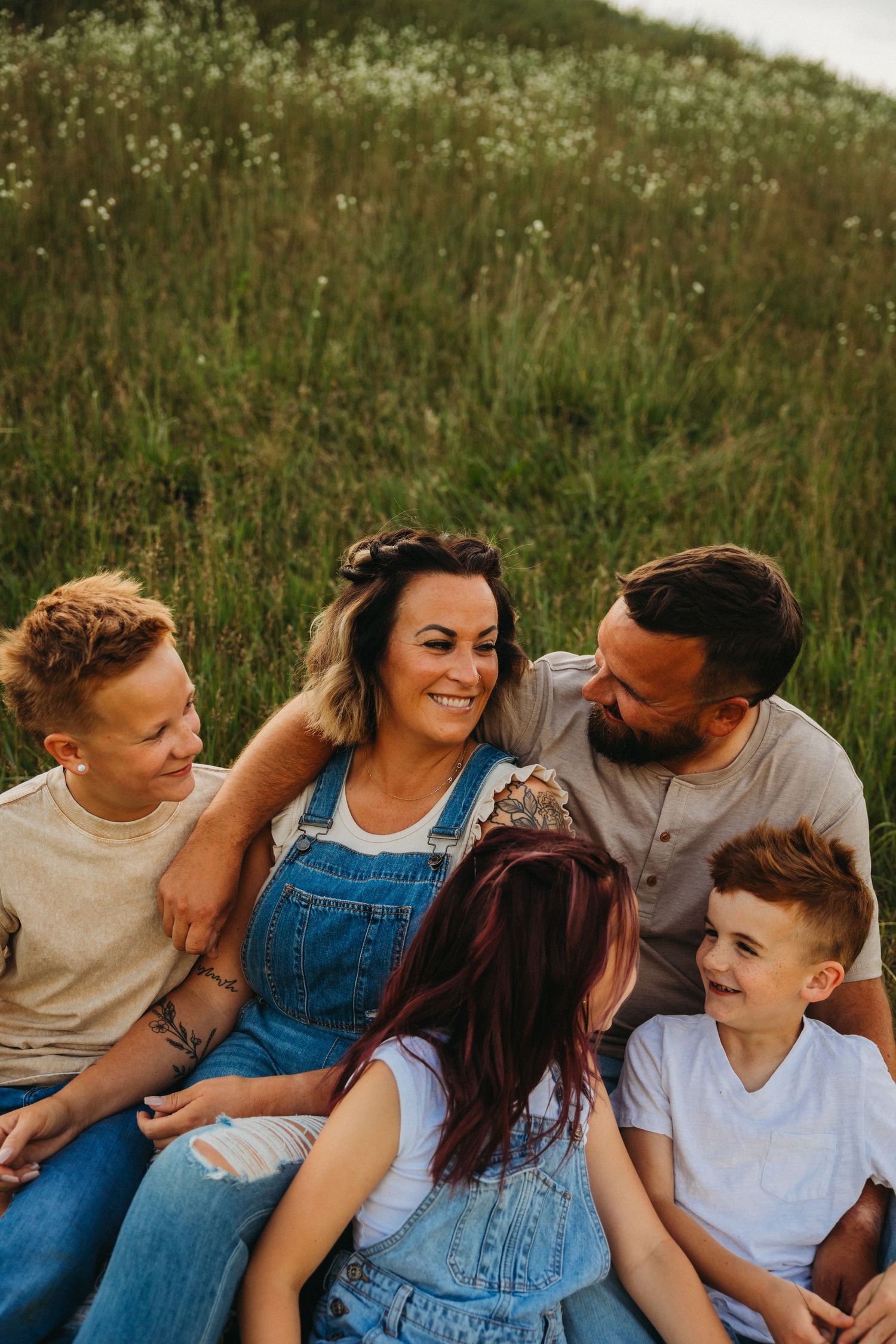 Happy group sitting together on grassy hillside sharing joyful moment.