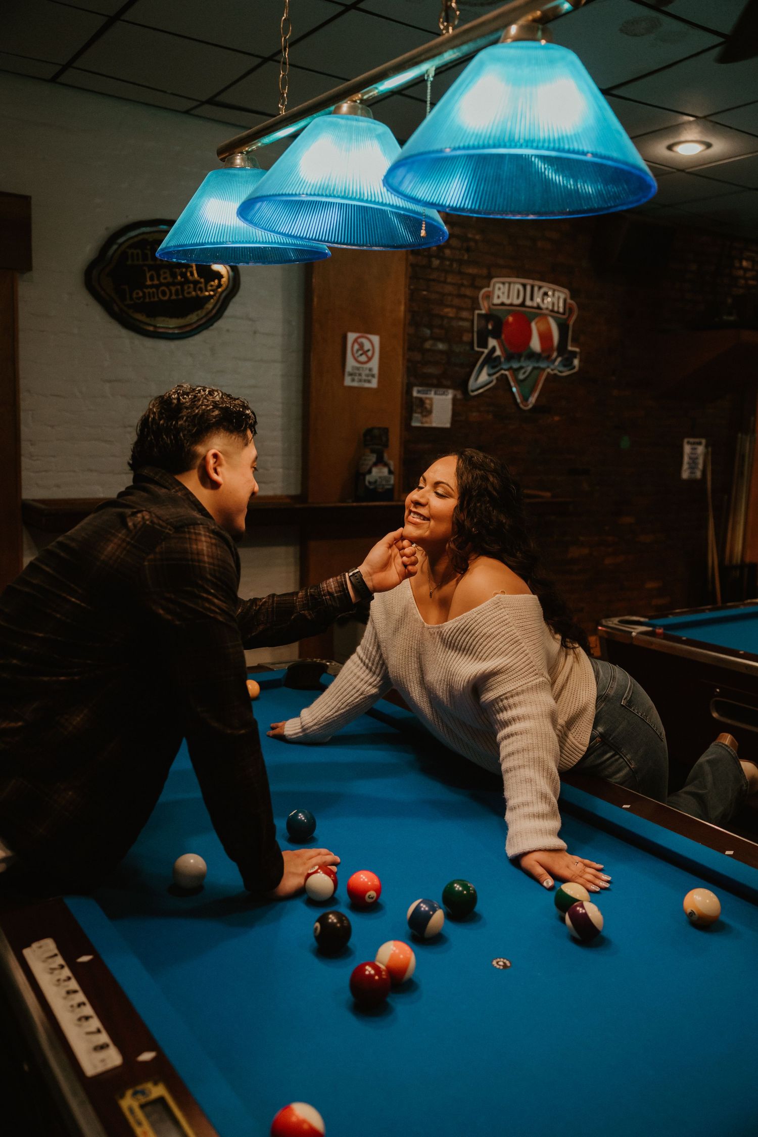 A playful scene at a pool hall with blue pendant lights illuminating the game table.