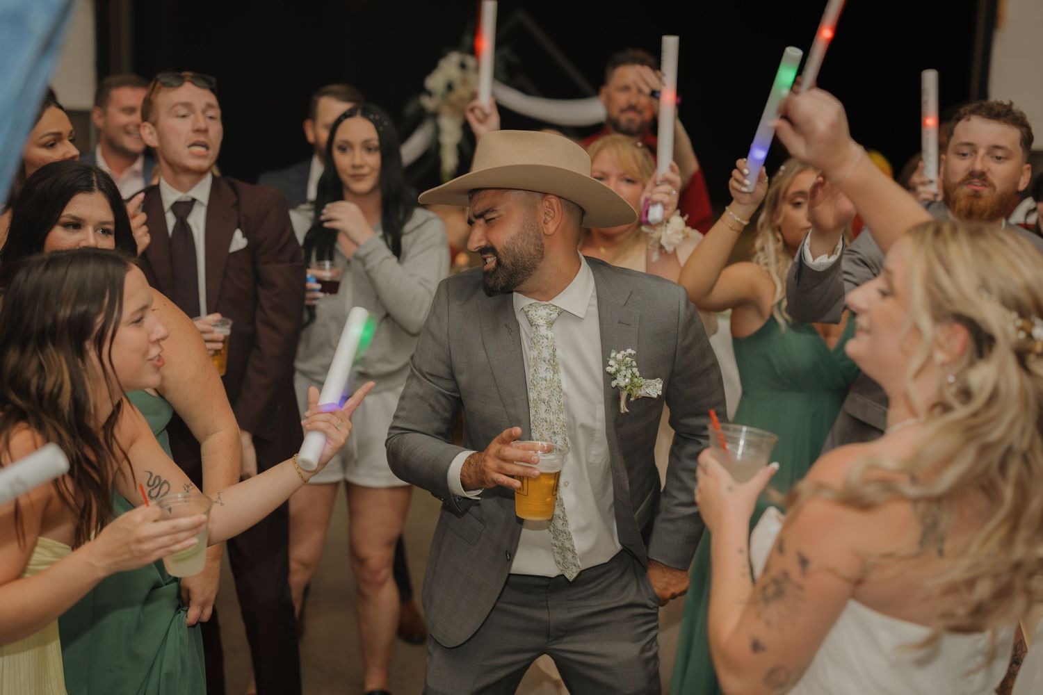 Wedding reception party with guests dancing and celebrating with glow sticks.