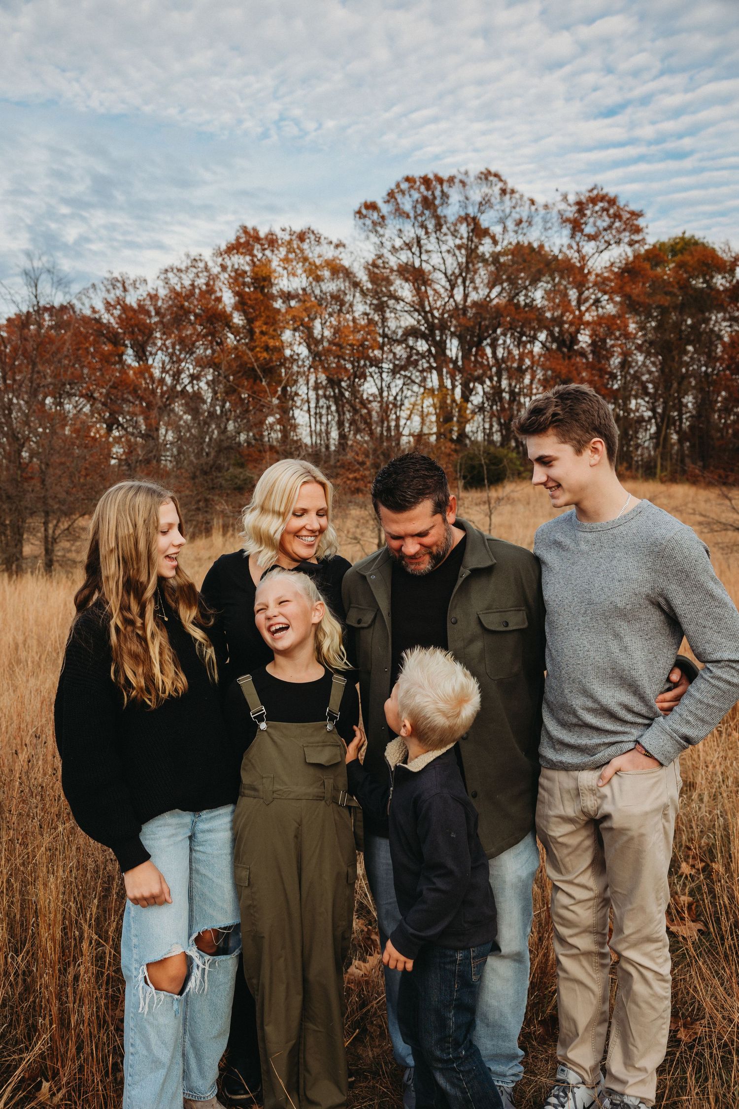 A group sharing laughter together in a golden autumn field with trees in the background.