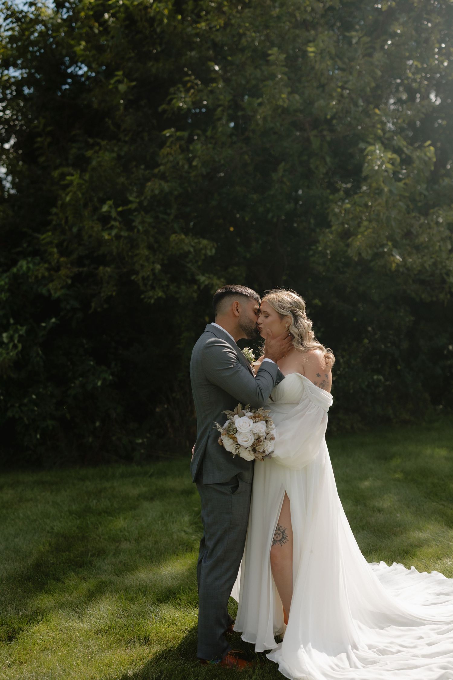 Romantic wedding couple shares an intimate moment in sunlit garden setting.