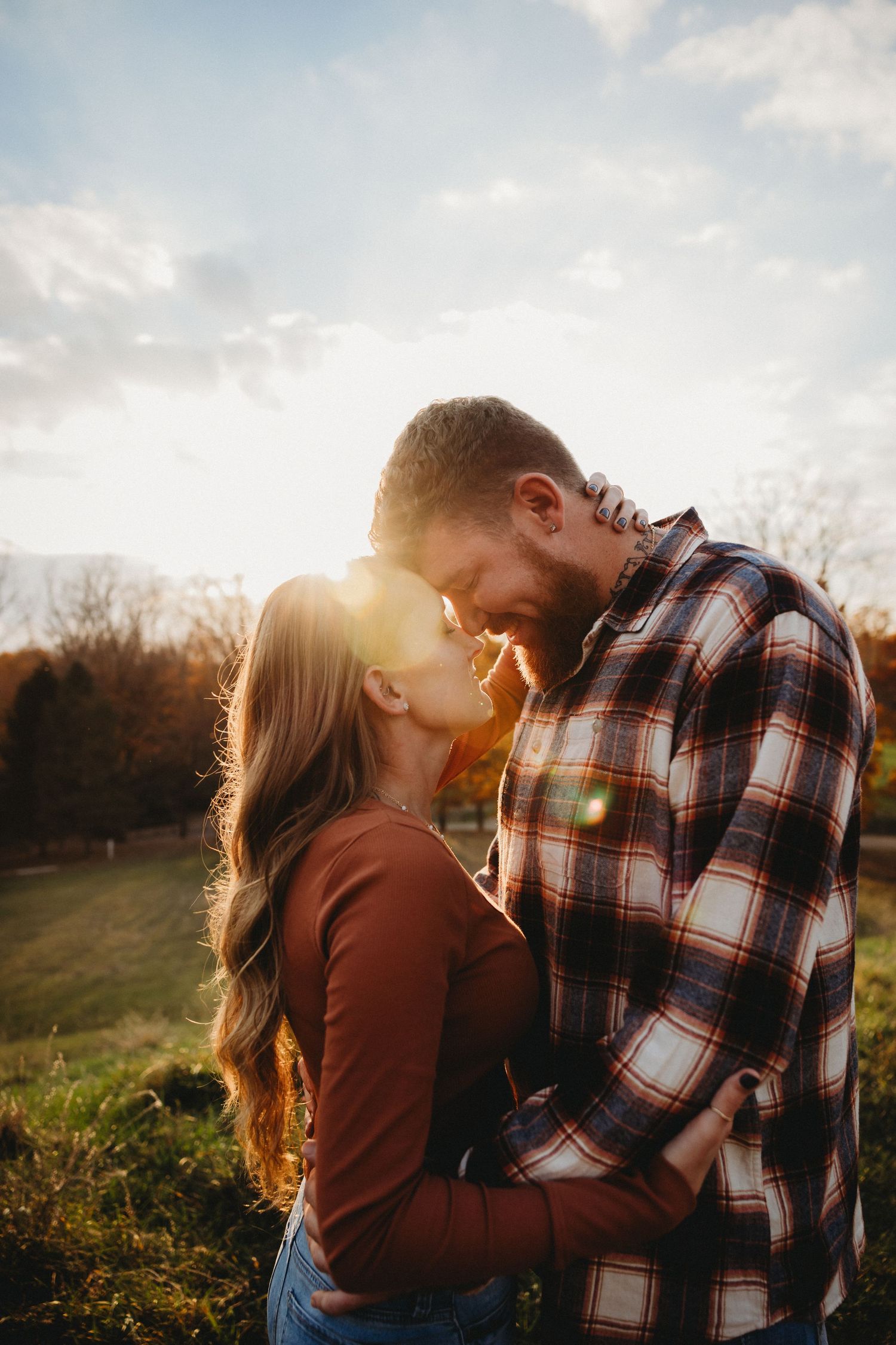 Romantic couple embracing in autumn field during golden sunset.