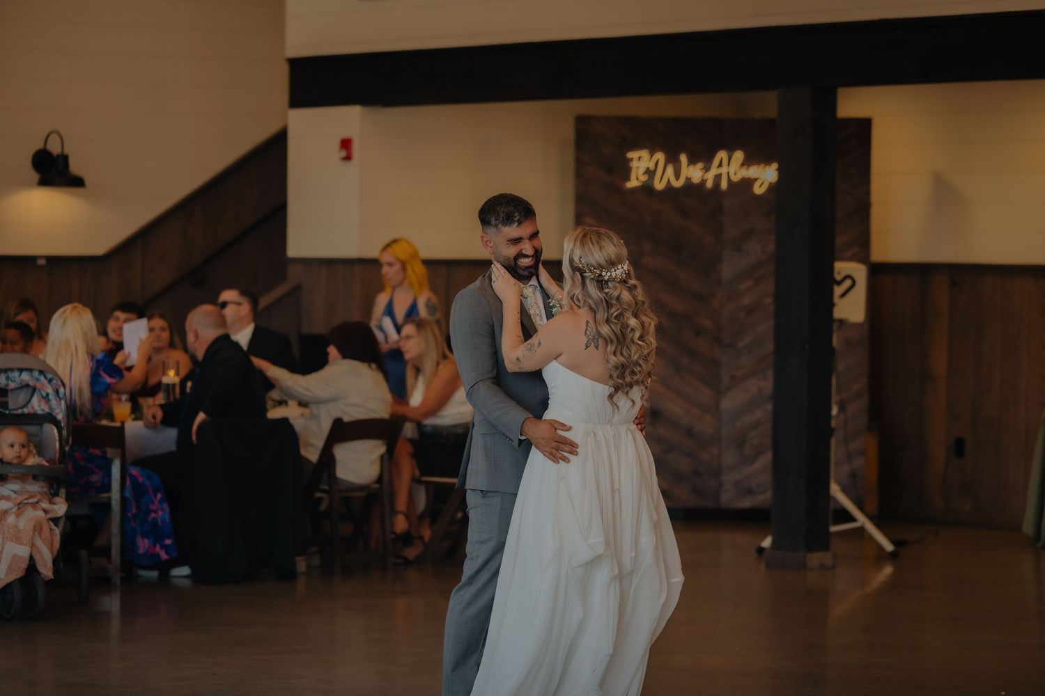 A couple shares their first dance at a wedding reception in an indoor venue.