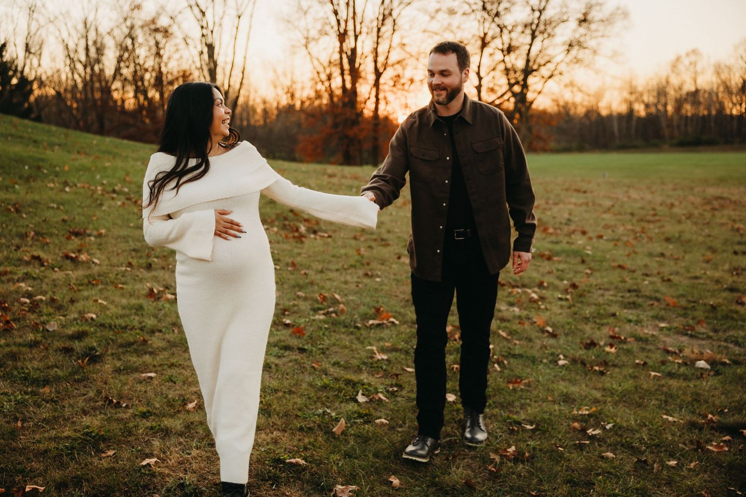 Romantic photoshoot in fall setting with couple walking through fallen leaves.