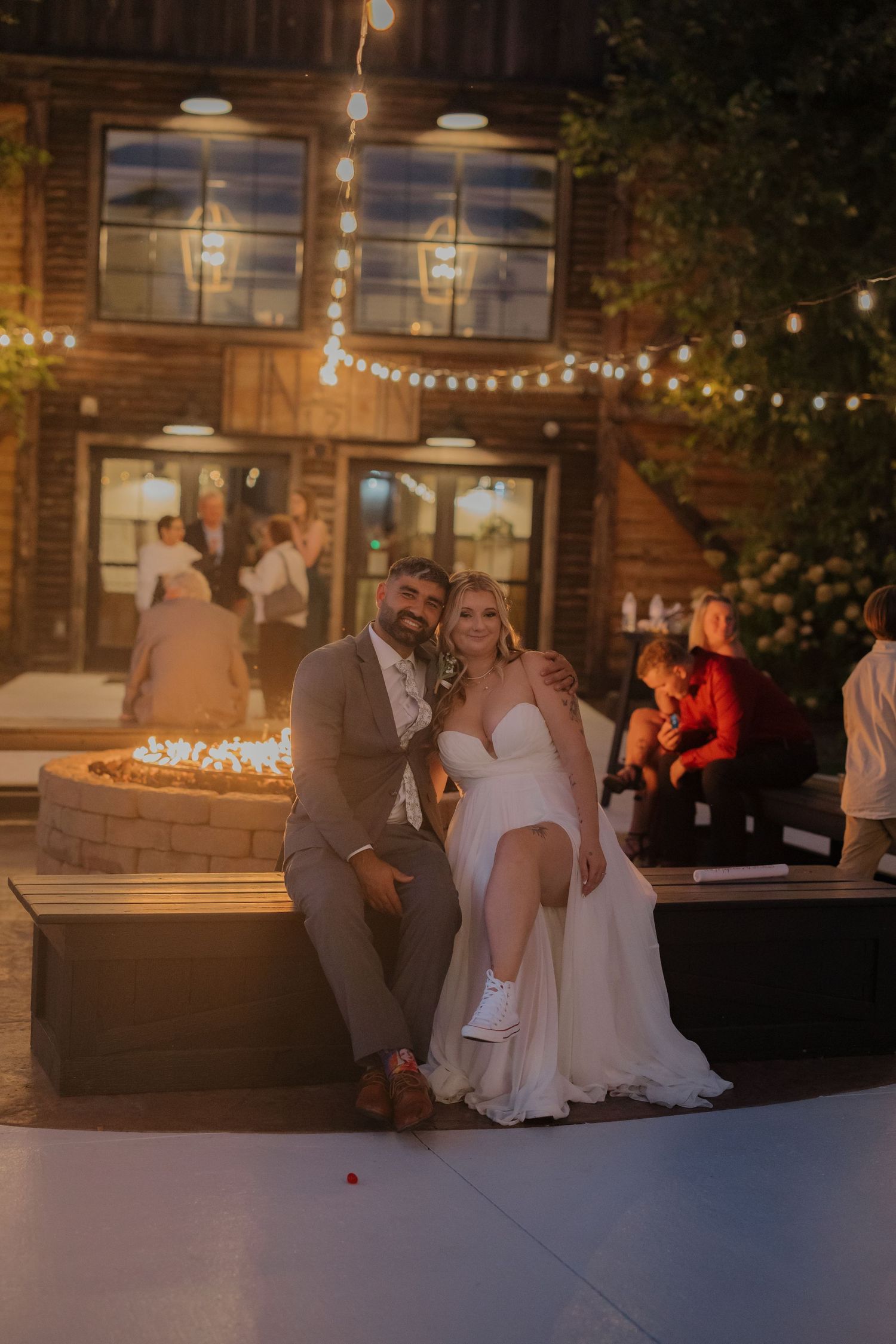 Evening wedding reception outside rustic venue with string lights creating romantic ambiance.