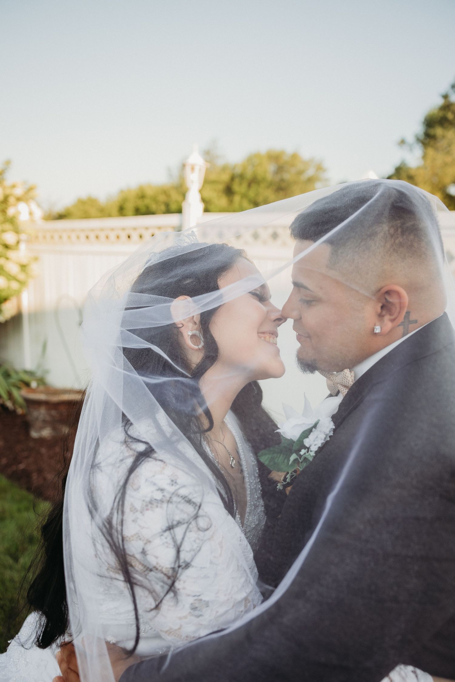 Romantic wedding portrait of a couple under a delicate veil with natural light filtering through.