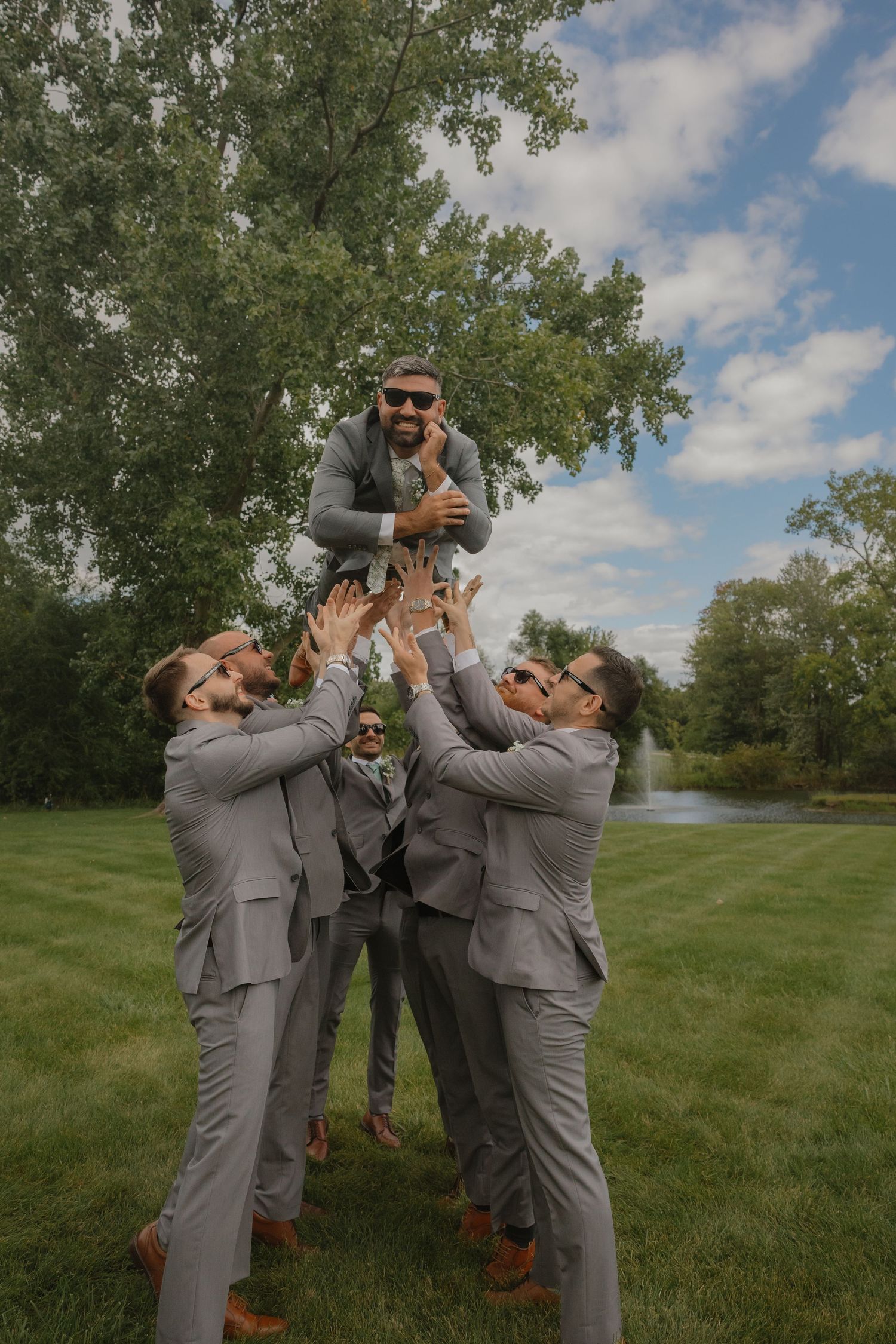 Groomsmen in grey suits having fun taking photos outdoors.