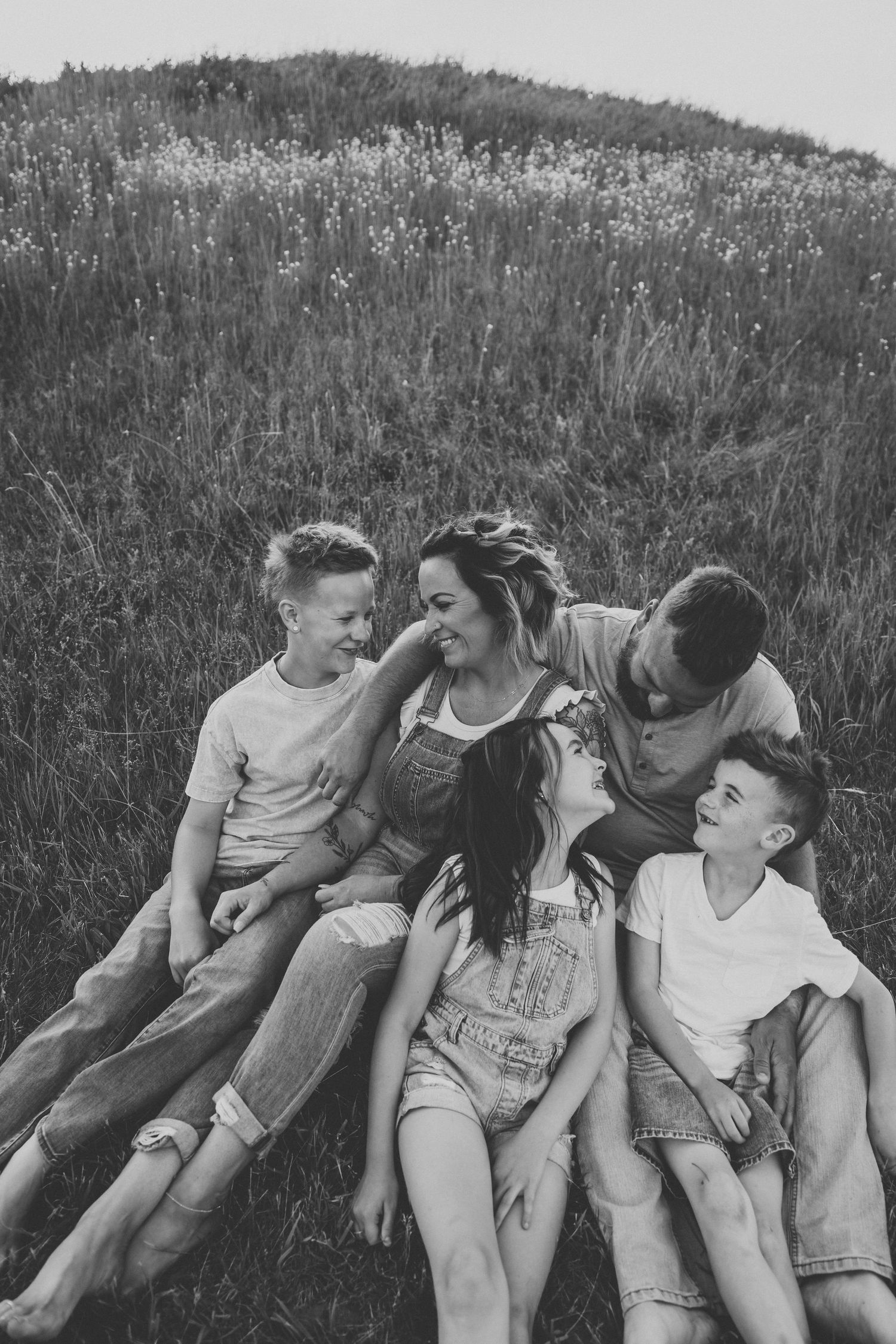 Black and white portrait of group sitting close together on grassy hillside.