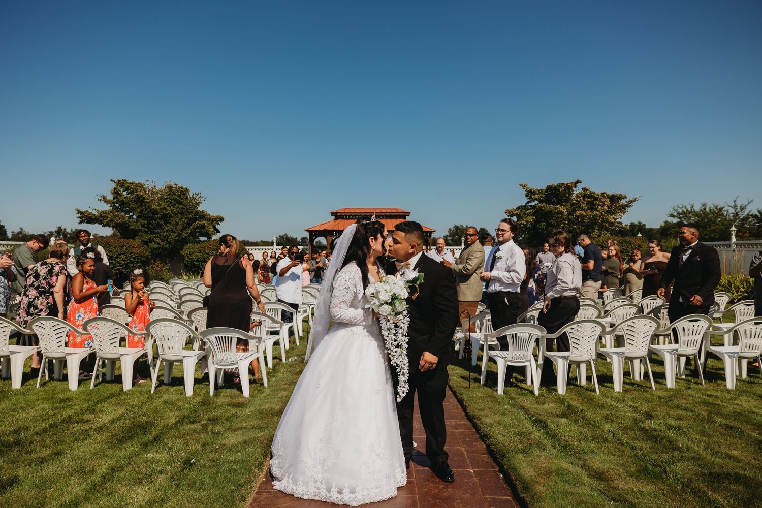 Newlyweds celebrate during their outdoor wedding ceremony surrounded by guests.