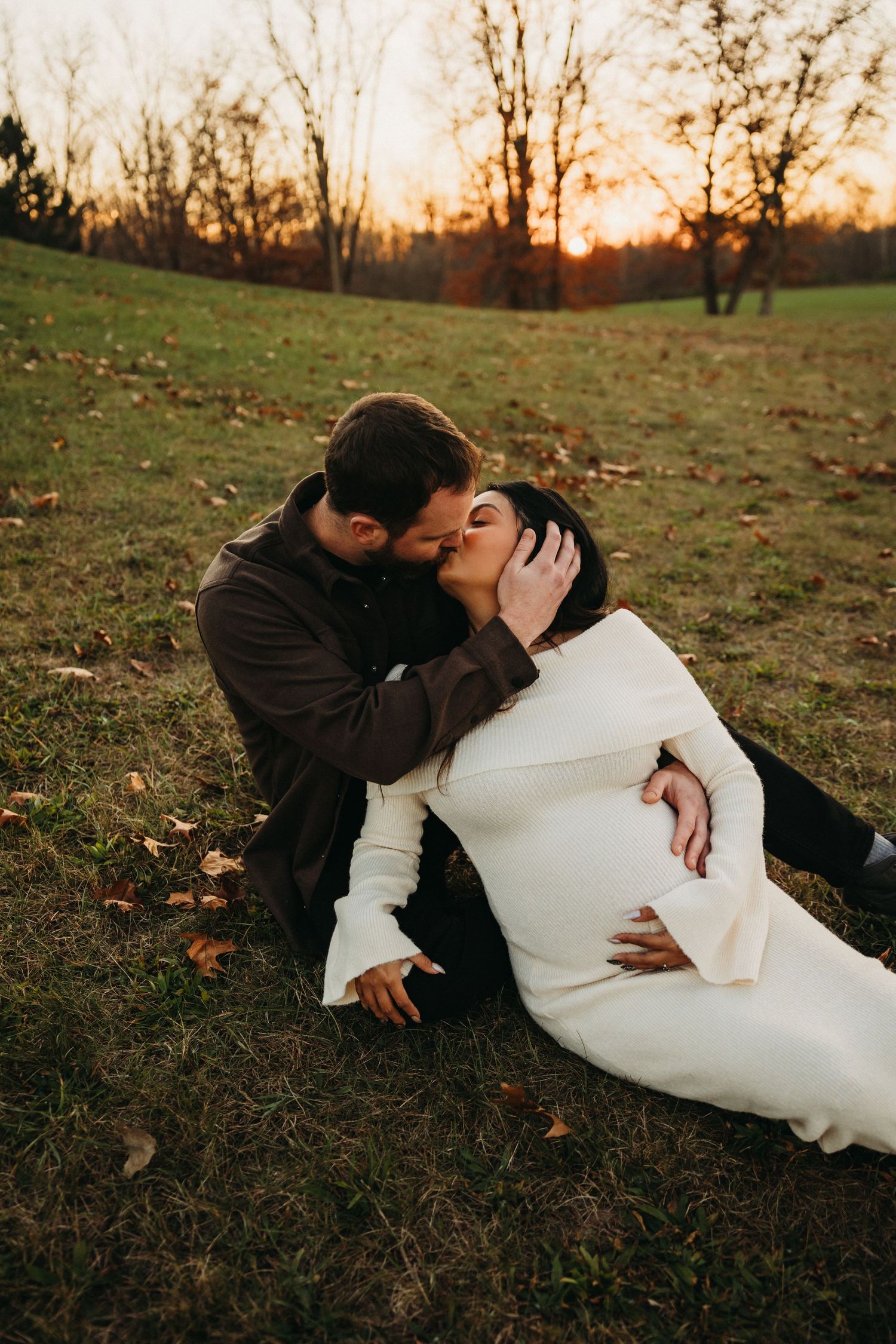 Intimate couple lying on autumn grass during golden hour sunset photoshoot.