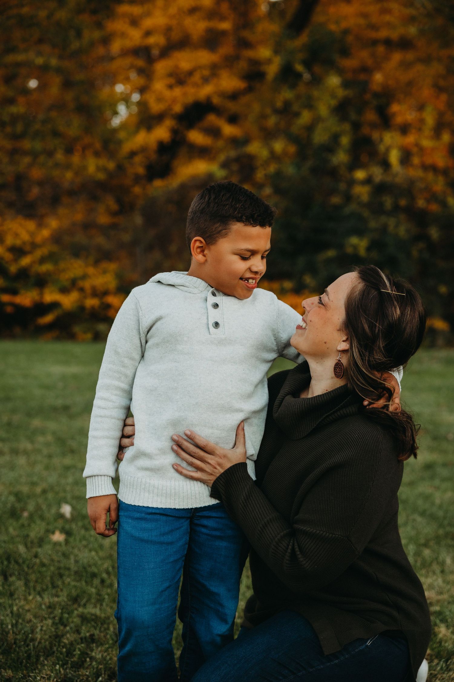 Intimate mother-child portrait with warm expressions against autumn outdoor backdrop.