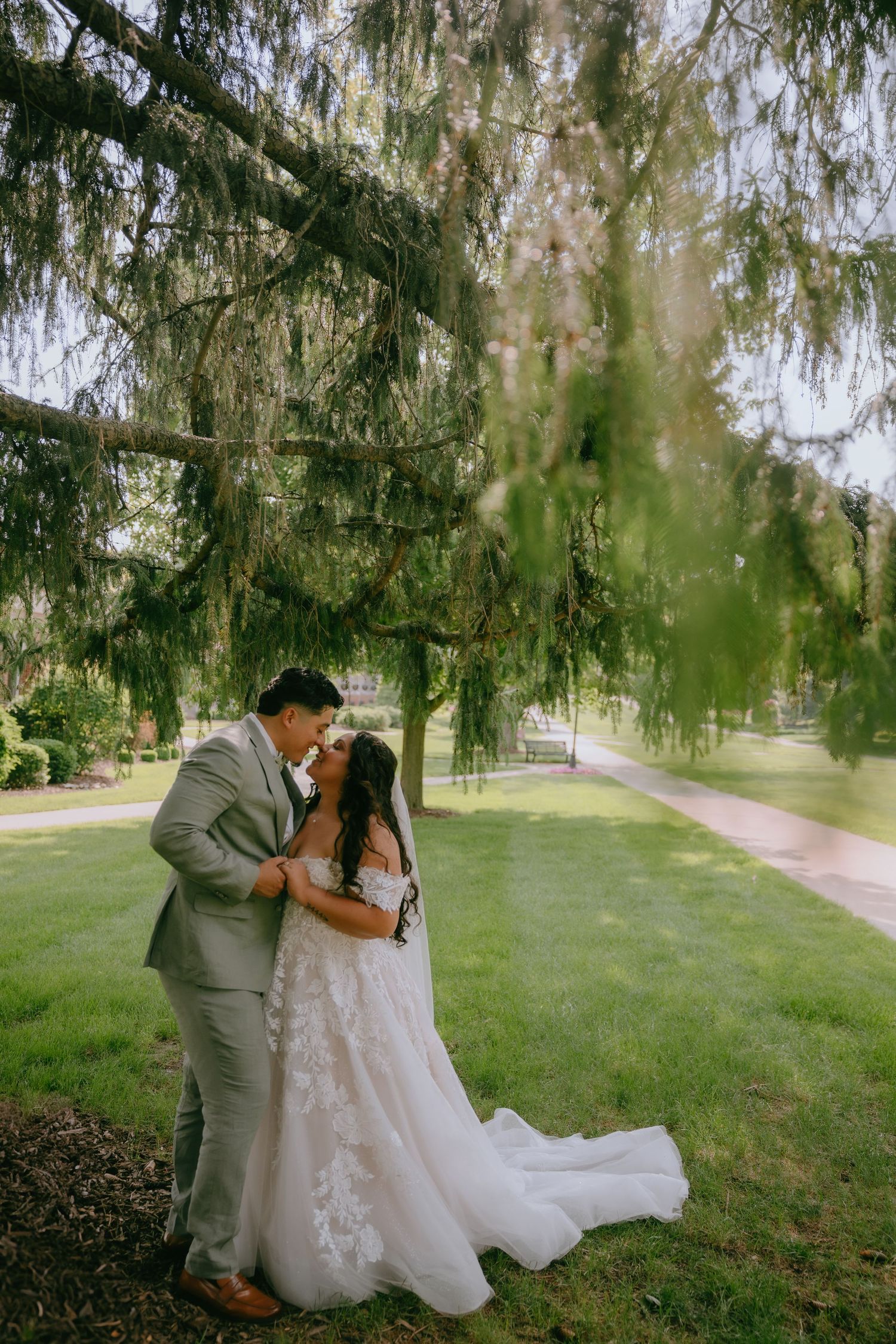 A romantic outdoor wedding photoshoot sequence showing a couple in formal attire embracing under willow trees in a park.