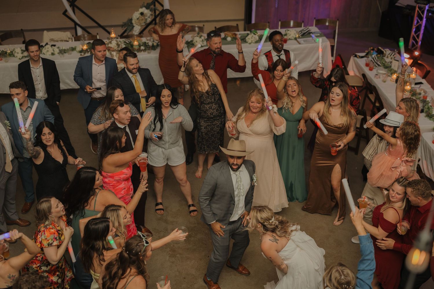 Wedding reception dance party with crowd of guests celebrating on dance floor.