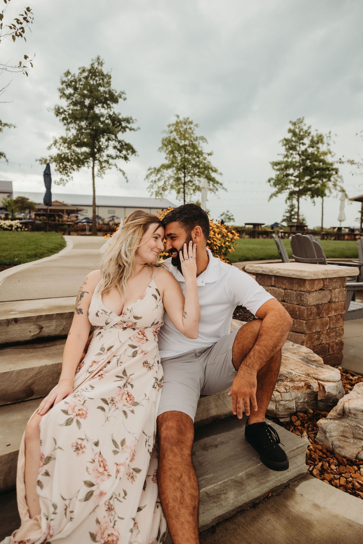 A romantic moment shared on stone steps with waterfront and trees in the background.