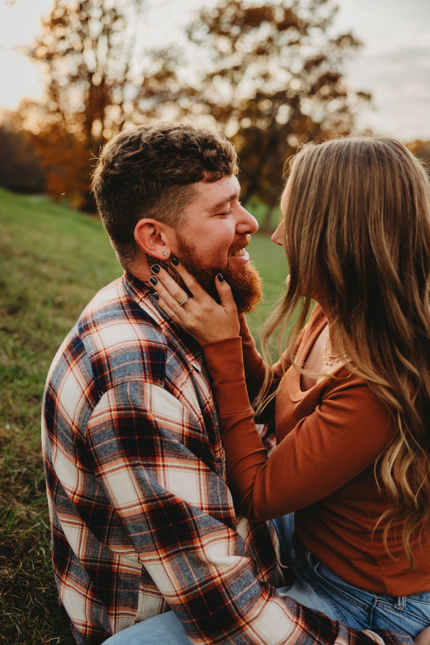 Intimate moment between couple in plaid and autumn colors against natural backdrop.