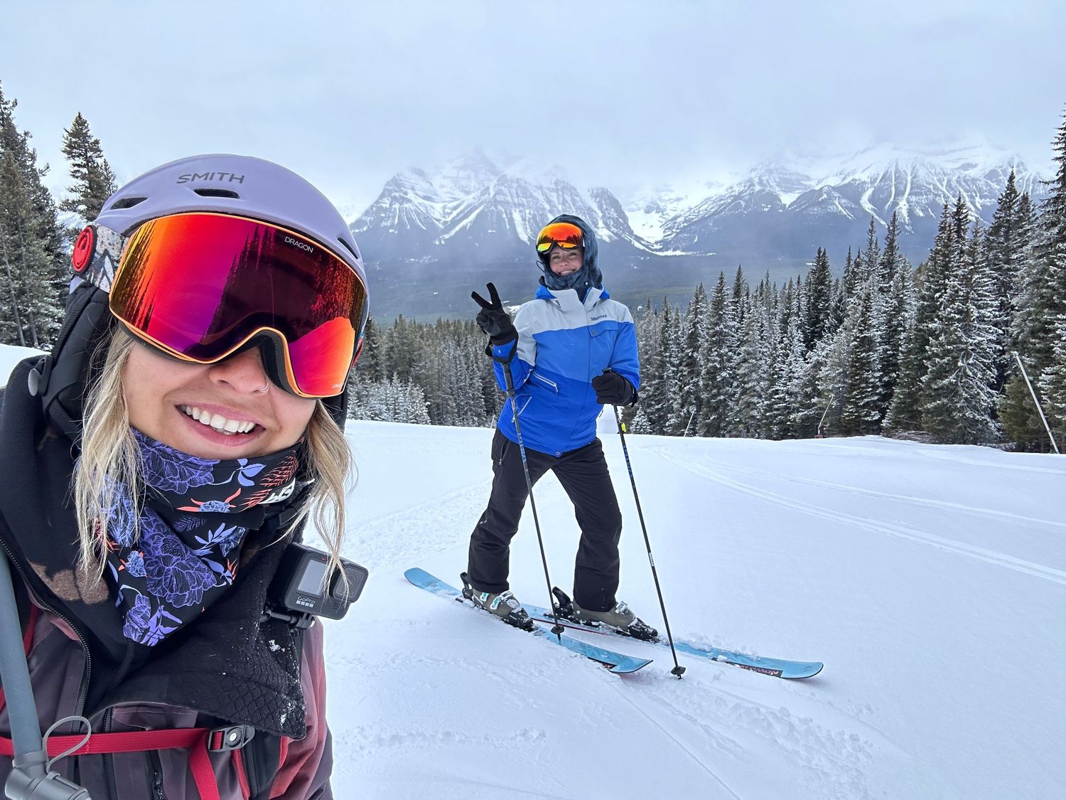 Two skiers enjoying a winter day on snowy slopes with majestic snow-capped mountains in the background.