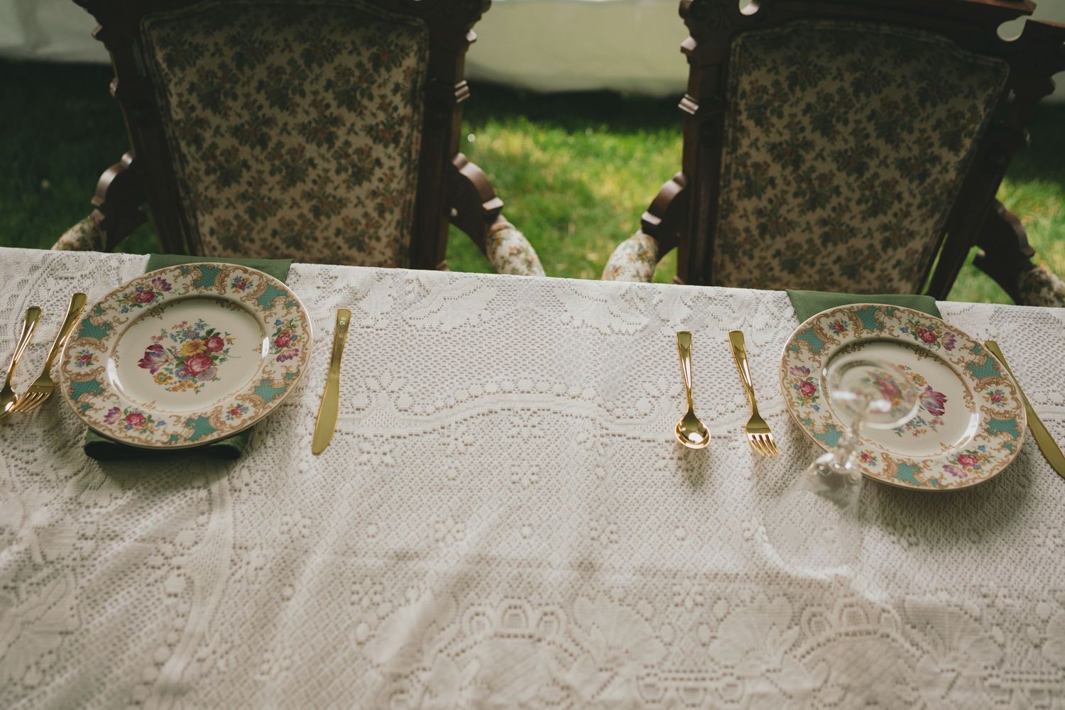 Vintage floral china plates and teacups displayed at an elegant outdoor garden tea party setting.