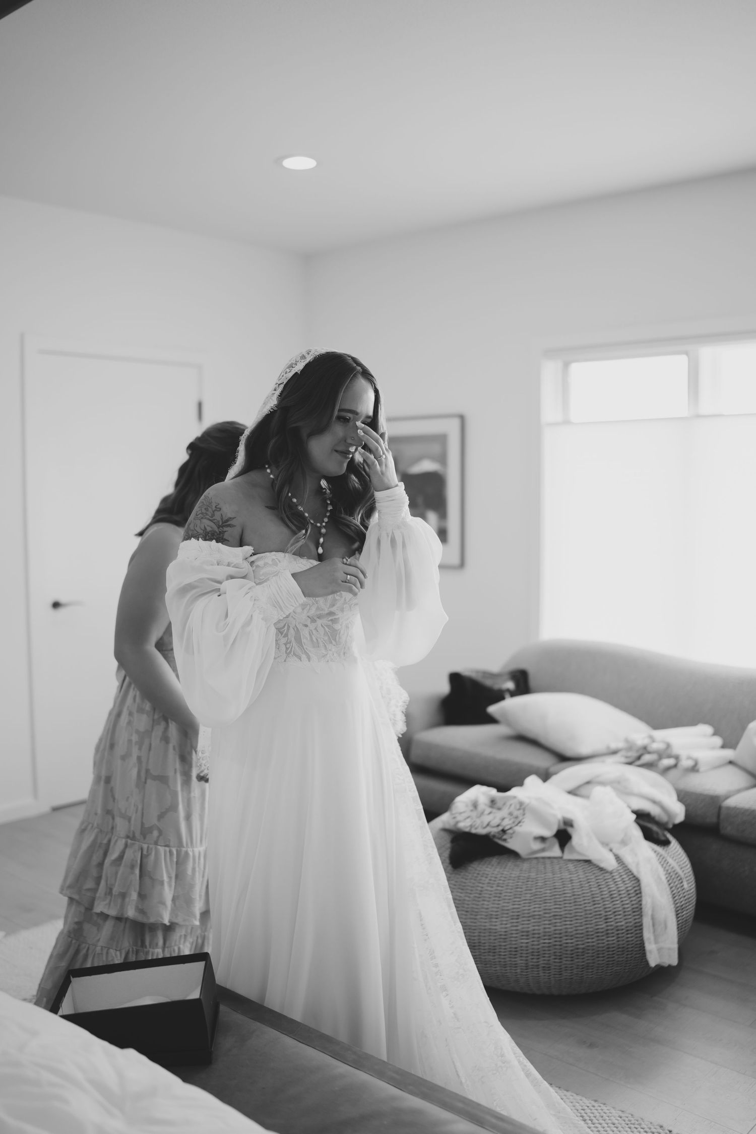 A series of black and white photos showing someone admiring a white dress in a bright modern bedroom.