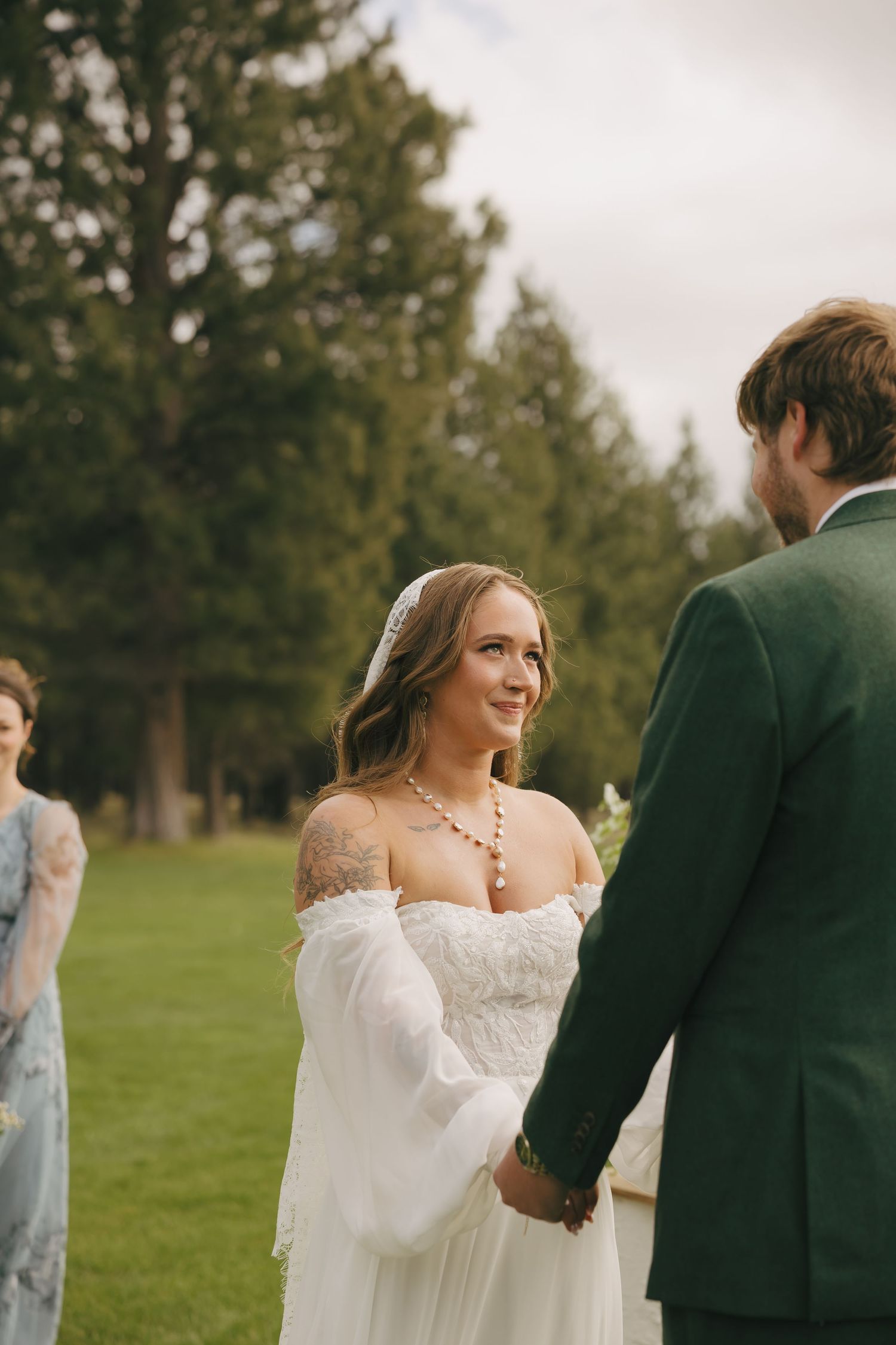 Wedding couple sharing an intimate moment during their outdoor ceremony with pine trees in the background.