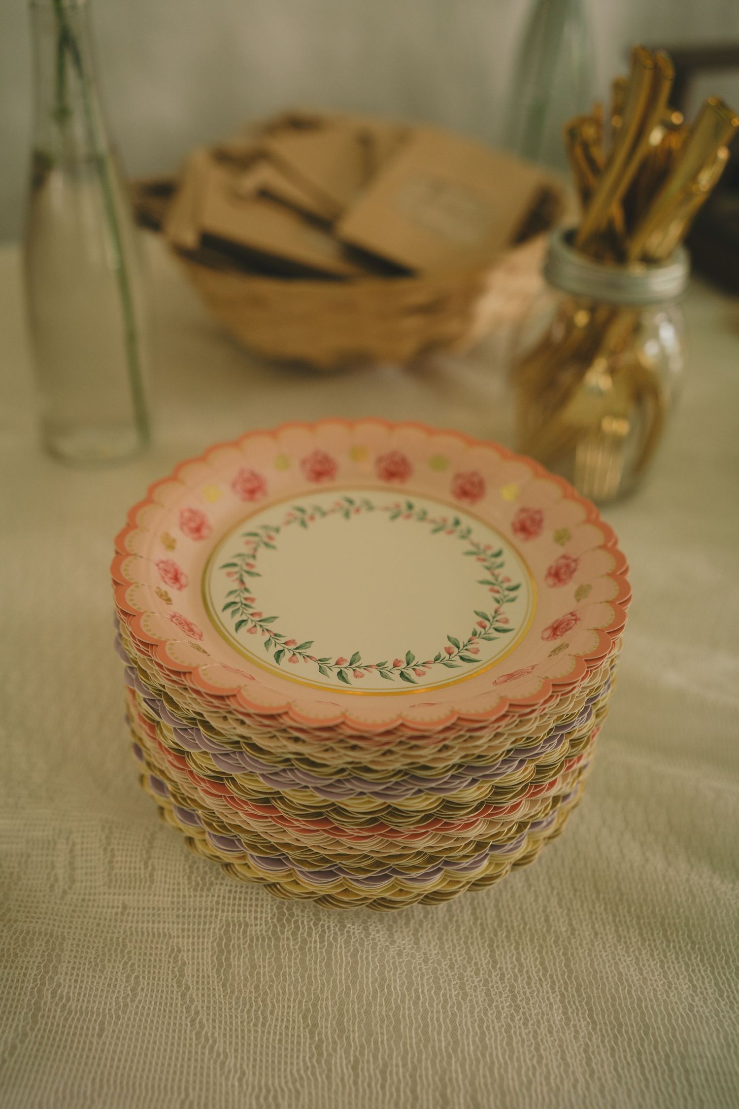 A collection of vintage-style paper plates with delicate pink floral patterns and scalloped edges stacked together. garden wedding