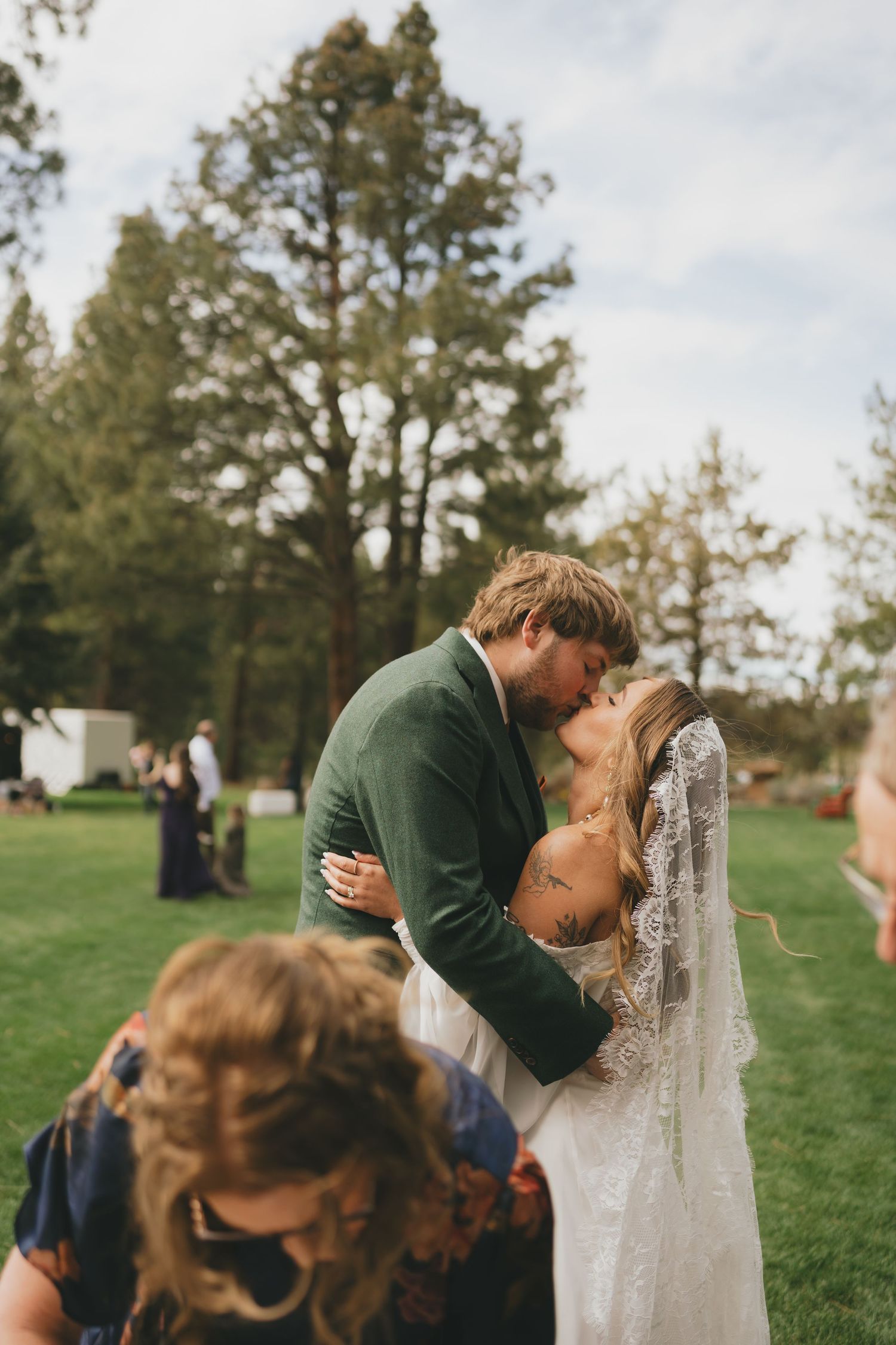 A couple shares intimate moments during their wedding photoshoot on a green hillside.