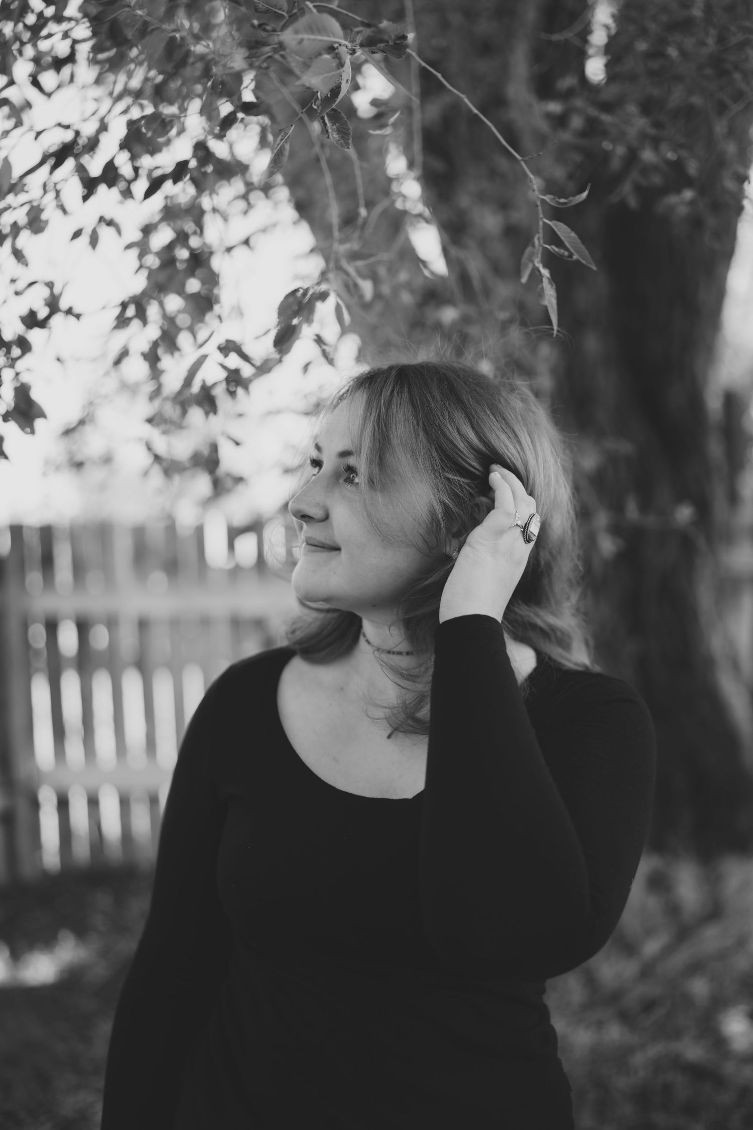 Black and white portrait showing contemplative pose under tree branches. Jessicamh Productions