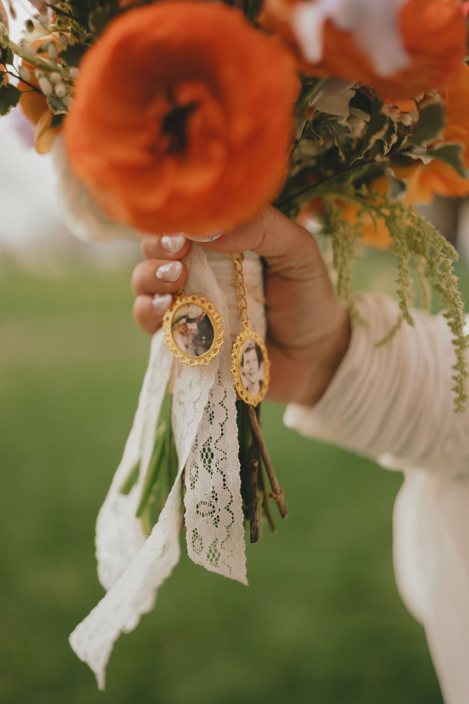 Close-up of orange flowers in a bouquet with delicate lace ribbon detail against a soft green background.
