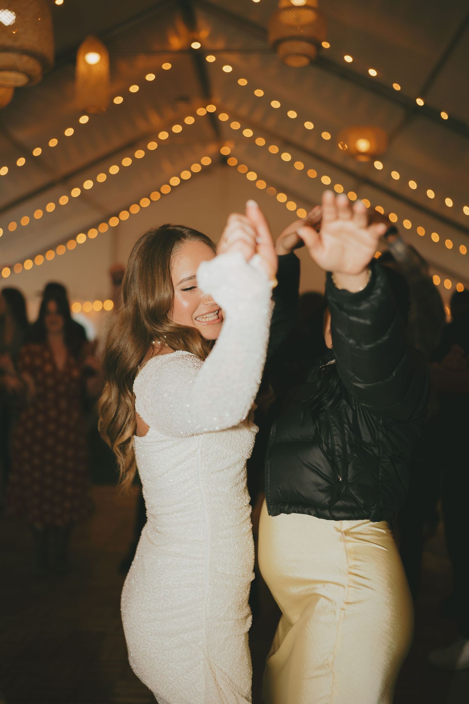 Wedding celebration with dancing under warm string lights and decorative ceiling decor.