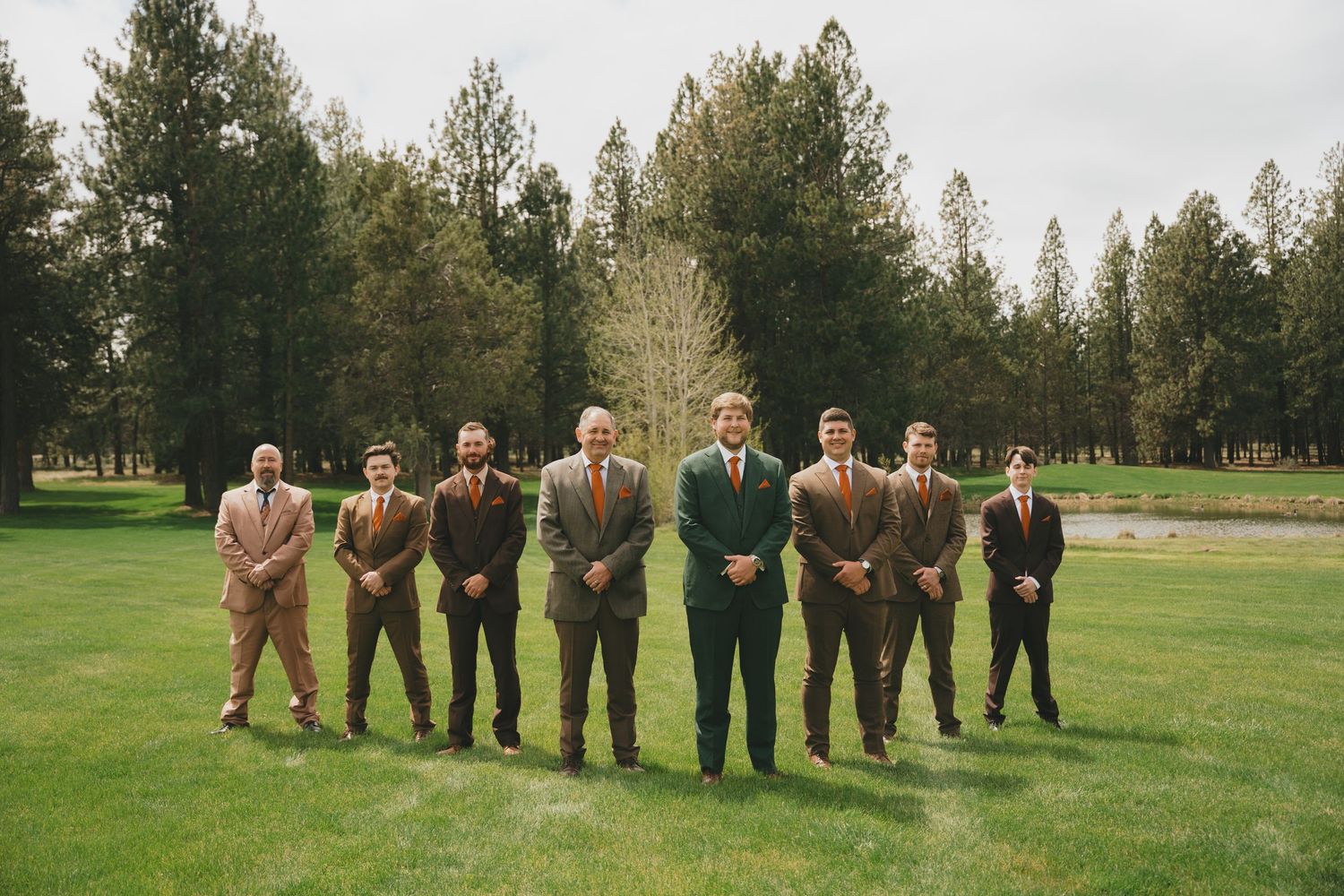 Wedding party members lined up on a lush green golf course lawn for group photos.